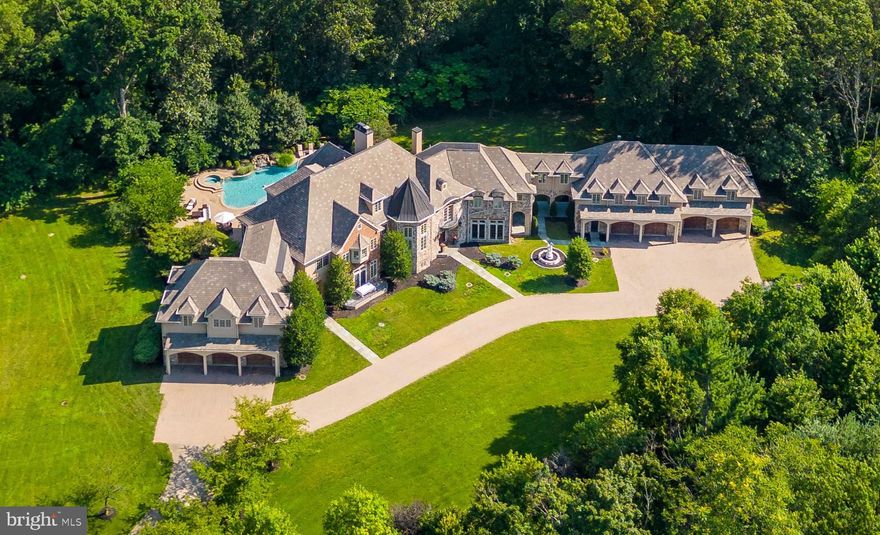 Welcome to this luxurious and elegant enclave set on 6.5 private acres in the heart of Lafayette Hill, 1.5 miles from the heart of Chestnut Hill. A gated drive leads up to this gorgeous, secluded stone home, replete with exceptional features and craftsmanship throughout. As you step inside the grand 2-story foyer, your eyes will be drawn to the exquisite Brazilian Cherry hardwood floors, and stunning crystal chandeliers above. The gourmet kitchen is a chef's dream, featuring a large island, 6-burner Viking stove with grill, double Viking oven, Sub-Zero refrigerator, Viking wine fridge, and Viking microwave. Enjoy the warmth of the huge stone double-sided gas fireplace that connects seamlessly to the spacious living room. The living room is a stunning 2-story space lined with surrounding glass-paned French doors, providing enchanting views of the large rear deck. The large formal dining room is perfect for hosting your favorite holidays with family and friends and is enhanced by a cozy gas fireplace and French doors leading to the front terrace. The piano room is filled with light, creating an inviting ambiance for music enthusiasts or simply for relaxation. Two gorgeous half baths add convenience to this floor, while the beautiful home office, lined with built-ins and featuring a gas fireplace, provides a functional and elegant workspace. Upstairs, the sunlit primary bedroom suite, with spectacular vaulted ceiling, features a gas fireplace, seating area, and private deck overlooking the pool below. The large walk-in closet ensures ample space for your wardrobe, and the ensuite bathroom boasts double vanities, a walk-in shower, and a separate soaking tub for indulgent relaxation. This section of the home offers two additional bedrooms, each with walk-in closet, and jack and jill bathroom. A separate bedroom suite, as well as two more bedrooms sharing a bath can be found on the second floor. The laundry room is equipped with two washers and two dryers for added convenience. Walking down the beautiful hallway you will enter the exercise room, complete with a gas fireplace and private balcony, which is connected to a bonus room/private family room, providing versatile space for various activities. The third floor provides additional living space and functionality, including a seventh bedroom, with an ensuite bathroom and walk-in closet, ideal for guests seeking privacy. A secondary office offers a quiet space for work or study. You can take the elevator to the lower level of this home where you will find a haven of entertainment and leisure, featuring a game room with space for a pool table or other activities. Adjacent to the game room, a sitting room offers ample space for entertainment and relaxation in front of the cozy gas fireplace. The bar area, with custom blue granite countertop, is the perfect spot to mix drinks and create lasting memories. A home theater with 15 luxurious seats provides the ultimate cinematic experience, making movie nights unforgettable. A full bathroom ensures convenience for everyone using this level. Walk out to the breathtaking outdoor oasis, where the over-sized pool area invites you to relax and unwind, with a shallow basking area, waterfall, and hot tub. A built-in Viking BBQ grill and mini fridge are perfect for outdoor cooking and dining, while the fireplace allows for enjoyment even on cooler evenings. Mature trees surrounding the yard provide complete privacy and a sense of natural beauty. The first-floor wrap-around deck offers additional outdoor living space, perfect for gatherings and relaxation. Multiple entertainment areas, a flat front yard, slate walkways, and a beautiful statue enhance the outdoor experience. Nestled on 6.52 acres of wooded land, this property also offers 7 cedar door garage spaces. The superlative location near major highways allows for an easy drive (24min.) to Center City, Philadelphia, NYC, or nearby towns for shopping and dining.