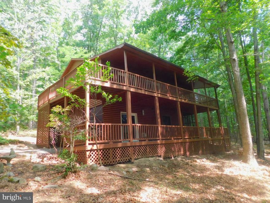 Tucked away in a secluded subdivision is this charming 2 BR 2.5 bath cabin on three wooded acres.  Relax and enjoy nature sitting on your porch  watching the deer and other wildlife.  Enter the front door at the lower level to a large foyer. There are two bedroom suites on the lower level and both suites open to a large relaxing porch. There is also a laundry closet with washer and dryer.  Walk upstairs to a open, spacious combination Great room, Dining room and Kitchen area and a half bath on this level. In the winter you can sit by the wood burning fireplace on the cold wintry days and nights.  Second level also has a huge screened in porch for entertaining.    Your guests will enjoy staying in the small guest cottage that has two single beds. Fishing, hiking and Lost River State Park are all minutes away.  Fresh gravel has just been put on the driveway.