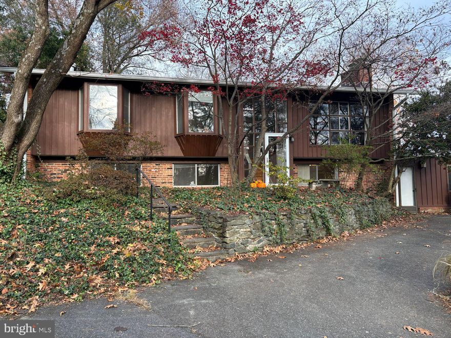Perched atop a hill, this spacious mid-century modern-inspired home offers elevated living with stunning natural surroundings. The expansive living room captivates with soaring vaulted ceilings, an exposed brick accent wall, fireplace nd floor-to-ceiling windows that frame serene treed views. The space flows seamlessly into a separate dining area, while brand-new sliding glass doors open to a  deck—your gateway to a beautifully landscaped, fully fenced backyard, a gardener's delight.
The kitchen balances form and function with a sunny eat-in area overlooking the yard, double wall ovens, electric cooktop, and included refrigerator. The primary suite is a true retreat, featuring backyard views, an exceptionally spacious walk-in closet, and a private en suite bath. Two additional bedrooms and a hall bath complete the main level, all anchored by warm hardwood flooring throughout.
The lower level expands your living space with a fourth bedroom, full bath, versatile rec room with exposed brick character, fireplace, a bonus room with separate entrances, perfect for a home office or gym, and practical utility/storage space.
Freshly painted from top to bottom, this home is move-in ready with kitchen and bathrooms primed for your personal design vision. A rare combination of architectural charm, functional layout, and natural beauty.