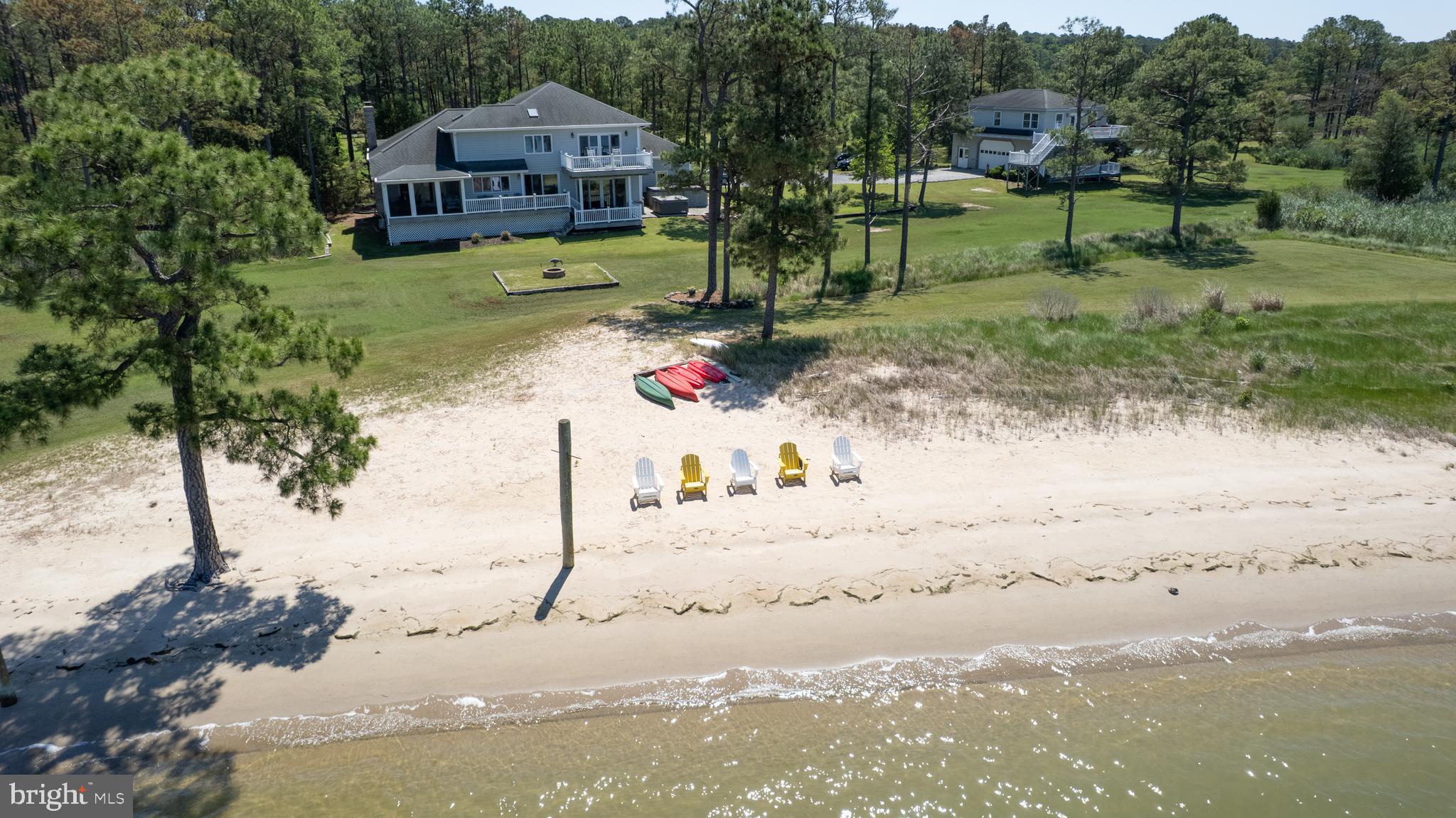 Beautiful waterfront on Madson Bay! Rarely do you find a property with your own private beach. This exceptional property checks all the boxes. 22+ acres. 10 acres are wooded, 2 ponds, 890 ft of shoreline, a sandy beach and a 3 bedroom, 2 bath guesthouse on the end of a private cul-de-sac. This impeccable home offers 4 bedrooms, 3 full baths, upper/lower decks, large screen porch, 3 car garage and a partial basement. When entering the foyer, to the right it opens up to the stunning living room with beamed cathedral ceilings, hardwood flooring, brick wood burning fireplace. The beautiful bay window enhances the room with natural sunlight. From the foyer to the left steps down to the stunning waterfront kitchen with granite countertops, stainless steel appliances, beverage cooler, induction cooktop, island, recessed lighting and beautiful view of the beach. To the right of the kitchen is the formal dining room with beamed cathedral ceiling, hardwood floors, built-in shelving. Off of the dining is the screened porch/sunroom with water views. To the left of the kitchen steps down to the family room. The family room is the heart of the home with hardwood floors, built-in shelving, double sliding glass doors that opens up to the large deck with broad water views and the sandy beach. The main floor also has 1-bedroom, full bath, laundry room and entry to the partial basement. The second floor offers the primary suite which spreads over the entire back of the home. Imagine waking up every morning to breath taking water views and the smell of fresh air. Enjoy your morning coffee on your private balcony or relax in the soaking tub in the gorgeous primary bath with views of Madson Bay. The large primary bath has 2 walk-in closets, skylight, double tiled shower and double sinks with granite countertops. To the left of the primary bedroom is a cozy sitting room where you can cuddle up, watch a movie or read a good book. The second floor also has a full bath with skylight and 2 bedrooms. HAVE I GOT YOUR ATTENTION? This waterfront Oasis is a MUST see. There is so much to enjoy. Boating, kayaking, canoeing, water skiing, fishing, crabbing, swimming or just relaxing on the sandy beach, swim spa and hot tub. Oh, did I mention the 10 acres of woods and 2 ponds and the abundance of wildlife that roams the property. Look out across the property and see Whitetail deer, Sekia deer, fox and turkey. The 2 ponds are filled with duck and geese and maybe a few fish. The guesthouse would make a great weekend rental or a get-away for family and friends. Main house or guesthouse has never flooded. You can get a permit for a pier. Water depth for pier is 5-6 ft on low tide. Click on the last photo for virtual video.
