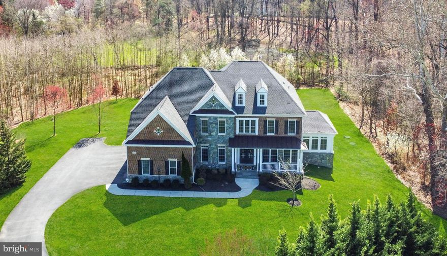 Welcome to 11033 Hunters View Road! This exquisite home is nestled in the Riverwood neighborhood on an expansive nearly 1-acre private, tree-lined lot. The charming stone and brick front colonial boasts over 8,126 sqft of living space and features a covered front porch entry along with an attached 3-car side entry garage. Upon entering, you'll be greeted by a grand 2-story foyer and a sweeping curved staircase. The main level offers spacious living areas adorned with stunning hand-scraped hardwood floors throughout. The gourmet kitchen is a chef's paradise, featuring an expansive center island, granite counters, decorative tiled backsplash, stainless steel professional-grade appliances (refrigerator updated 2021), recessed lighting, a butler's pantry with a wine refrigerator (2021), and a cozy casual dining area. Relax in the sunroom which boasts a tray ceiling and convenient deck access, perfect for enjoying your morning coffee. Entertain guests in the elegant formal living and dining rooms, complete with decorative columns, custom moldings, and an abundance of natural light. Adjacent to these spaces, a luxurious solarium with a tray ceiling offers a tranquil retreat. The impressive two-story family room showcases a soaring ceiling and a striking gas-burning stone profile fireplace. A study with French doors and a powder room completes the main level of this exceptional home, which is further enhanced by custom plantation shutters and quality upgrades throughout. Upstairs, the gracious master suite awaits, featuring a sitting room, tray ceiling, dual walk-in closets, and plush carpeting. Unwind in the remarkable master bath, boasting an oversized walk-in shower with pebble stone flooring and ceramic tile, dual vanities, and a relaxing soaking tub. Three additional generously sized bedrooms, a dual-entry bath, an en suite bath, and a convenient laundry room complete the upper level sleeping quarters. The lower level offers endless possibilities with an exceptional recreation room, fifth bedroom, full bath, media room, additional storage, and convenient walkout access. Outside, the expansive rear deck provides the perfect spot to watch the sun rise and set, overlooking meticulously manicured grounds and a scenic view. Don't miss the chance to make this phenomenal property your new home today! Conveniently located for commuters, this home offers both luxury and practicality.