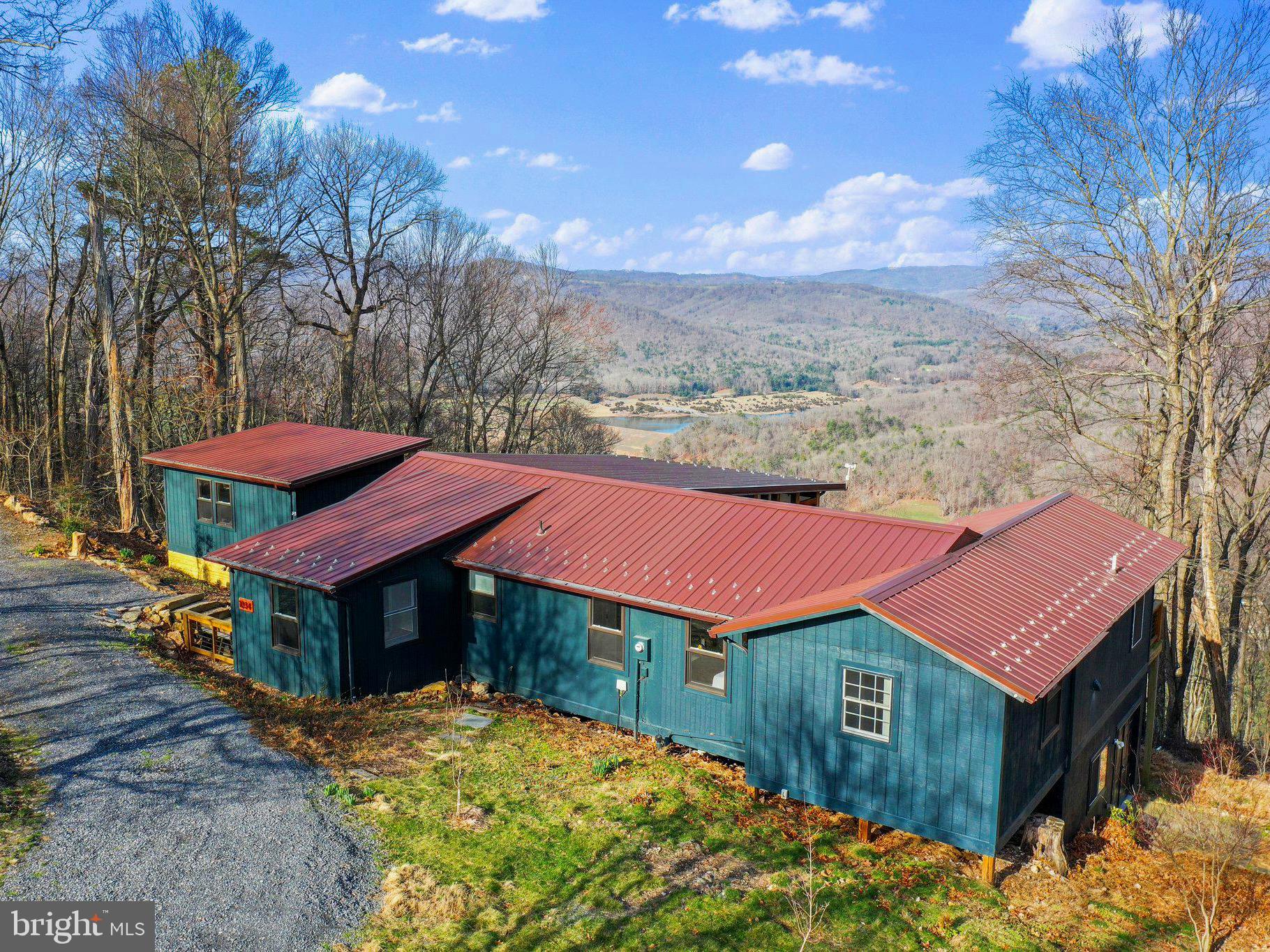 This fully re-imagined three bedroom mountain retreat perched high above the Lost River Valley offers the perfect blend of rustic charm and modern luxury. Situated on 10 acres of mountain land, this cabin boasts breathtaking views that stretch as far as the eye can see. From Bald Eagles soaring overhead to the tranquil waters of Kimsey Run Lake in the distance, every glance from this cabin's vantage point is a masterpiece of nature's beauty. The panoramic views of rolling mountains and vibrant sunsets define the experience of mountain living in the highly sought-after Lost River Valley Property Owners Association. Step onto the expansive screened porch, which doubles as an outdoor living and dining room, and feel the stress of the world melt away. Inside, an open floor plan welcomes you with abundant natural light streaming through oversized sliding glass doors. The kitchen is a chef's dream, featuring soapstone counters, stainless steel appliances, and vaulted pine-clad ceilings that add warmth and character to the space. The living/dining area is adorned with ship-lap wall accents and a cozy stone fireplace, creating the perfect ambiance for gatherings with friends and family. A detached 1-bedroom studio guest suite with a half bath offers additional space for visitors or serves as a dedicated home office or art studio. The primary bedroom suite is a sanctuary unto itself with custom glass windows & sliding glass doors that frame the majestic mountain, pasture & lake views and features a luxurious ensuite bathroom with a walk-in closet and laundry. Wraparound decks create a seamless transition between indoor and outdoor living, allowing you to bask in the fresh mountain air and enjoy the tranquility of your surroundings. Whether you're savoring your morning coffee as the sun rises over the mountains or stargazing under the vast night sky, these decks provide the perfect backdrop for every moment. For those seeking versatility, the walk-out basement offers bonus space currently used as a workshop/gym but can easily be transformed to suit various needs. A large dedicated entry room provides extra flexibility and could easily serve as a home office or mudroom. Additionally, a level 2 electric charging station is available for eco-conscious residents. Whether you're seeking a peaceful retreat or an outdoor enthusiast's paradise, this cabin in Lost River, WV, offers a lifestyle unlike any other. Come experience the magic of mountain living in this stunning, fully renovated home. This mountain retreat offers modern conveniences for today's lifestyle, including high-speed fiber optic internet and all underground utilities, ensuring seamless connectivity. Additionally, the property is just a few miles away from the esteemed Guesthouse Lost River, with access to additional services, entertainment and an award winning restaurant, further enhancing the experience of mountain living. Lost River, WV has many local shops, markets, boutiques, and restaurants, providing easy access to daily essentials and leisure activities. Visit the Virtual Tour & Video-Walkthrough links to see this incredible home!