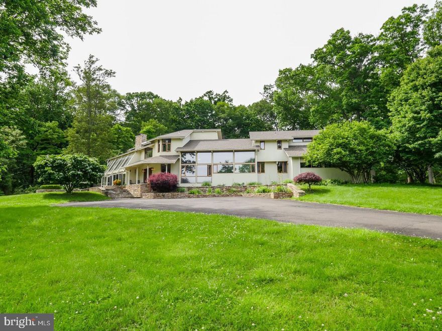 Everything you need in one serene family-sized compound: a stunning contemporary home, pool, and 10 lush acres with it's own pond. Set back from the road, the property is tucked away for privacy and tranquility.  The unique modern residence is highlighted by striking two-story living spaces and walls of floor-to-ceiling windows, providing stunning light and views overlooking the private grounds. Stone fixtures, exposed beams, and double height windows are on display throughout.  The chef's kitchen is a culinary dream with butler's pantry, 3 Jenn Air baking ovens, built-in Sub Zero refrigerator, and a thoughtful open-air layout ideal for entertaining. The main floor also includes a bedroom suite, with a private bath and jetted tub, as well as a well-appointed home office. Upstairs, retreat to your incredible Primary Suite, with a private balcony, dual walk-in closets, and gorgeous views. The Primary bath offers plenty of space, a dual vanity, jetted tub, and walk in shower. There are three additional bedrooms on the upper level, all with tree house style views. Downstairs, the full basement includes a bonus room, full bath, and access to the grounds, making the space versatile for use as a fitness room, studio, media room, or whatever suits your needs. An amazing find, and just 10 minutes away from downtown New Hope for acclaimed dining, shopping, and theater. Contact us for a showing!