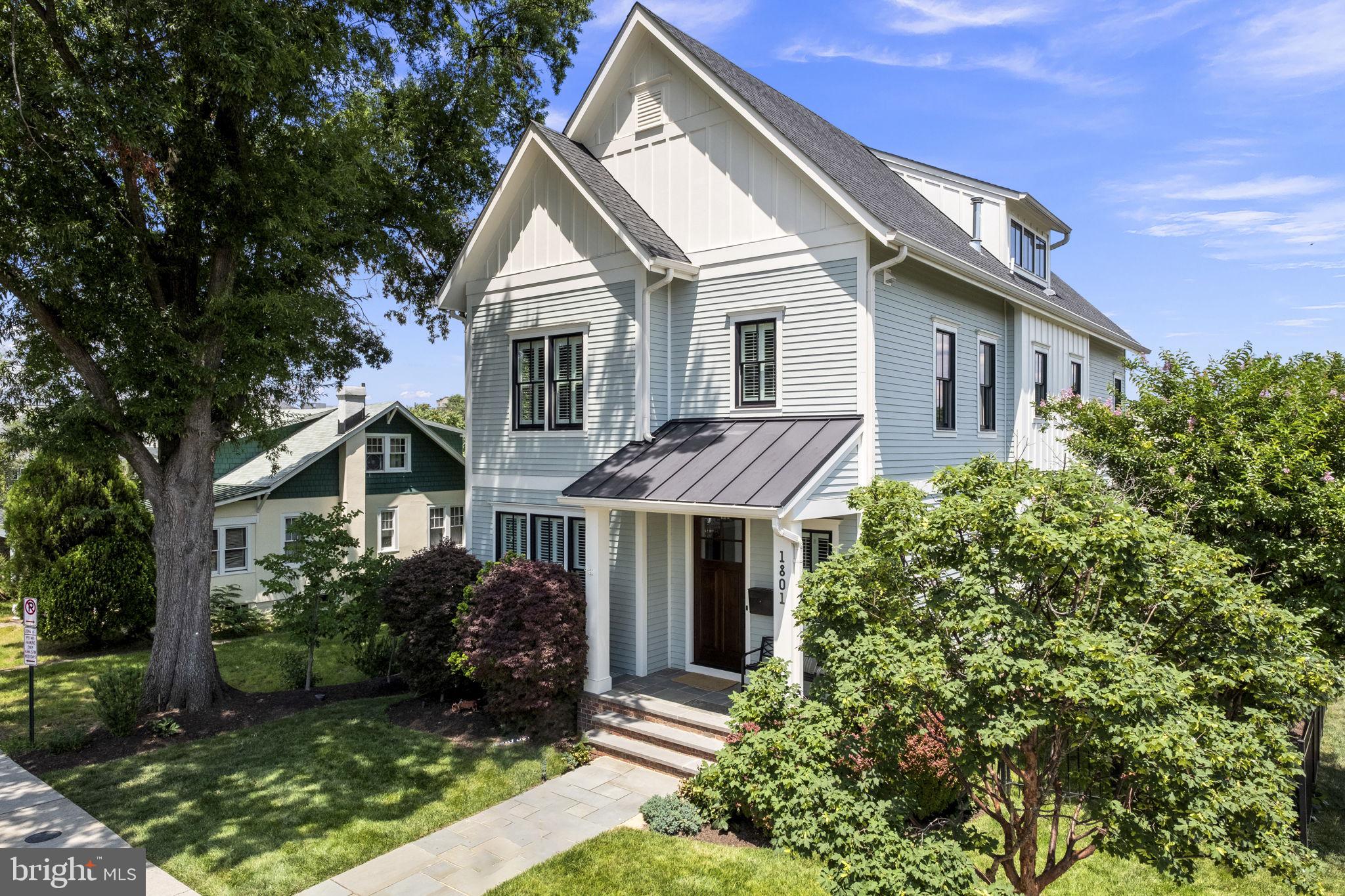 **Open houses are cancelled as the home is now under contract.**Designed by Thomas French and completed in 2017 by Spring Street Development, this residence offers a perfect blend of urban living and a tranquil retreat. With 4,979 square feet of living space, it occupies a corner lot with a southern exposure in Lyon Village, situated between Courthouse and Clarendon Metros. This home is walkable to shops, dining, groceries, schools, parks, and a vibrant city lifestyle, all less than two miles from DC.
Upon entering this four-level house, a light-filled foyer showcases stunning custom trim work and hardwood flooring which are found throughout. A flexible room suitable for a home office, dining area, or library is just off the entrance. A butler’s pantry connects this space to the kitchen and is outfitted with a beverage refrigerator, custom wine storage and a large pantry. The kitchen boasts striking blue accent cabinetry, a six-burner range and wall oven, a central island with a prep sink and seating, and opens to a welcoming dining space lined with windows and family room with a stunning coffered ceiling and gas fireplace. The mudroom with built in cubbies leads to the garage entrance.
The upper floor hosts the primary suite with two walk-in closets and a luxurious bath featuring dual vanities, a soaking tub, and a separate glass-enclosed shower. Two additional spacious bedrooms, each with an ensuite bathroom and a bright laundry room complete this level. A bonus room on the top floor offers southern views and has an additional bedroom and full bath.
The lower level, with 8’-9’ ceilings and ample natural light, features a gym and a wonderful living area for an au pair, in-laws, guests or ADU, which is registered with Arlington County. This space comprises a private one-bedroom, one-bathroom unit with a separate entrance, full kitchen, family room, laundry, and HVAC system. Outside, the landscaped and fenced yard with landscape lighting is easily maintained with an underground irrigation system. A detached one-car garage with keypad and remote adds convenience to this inviting home.
