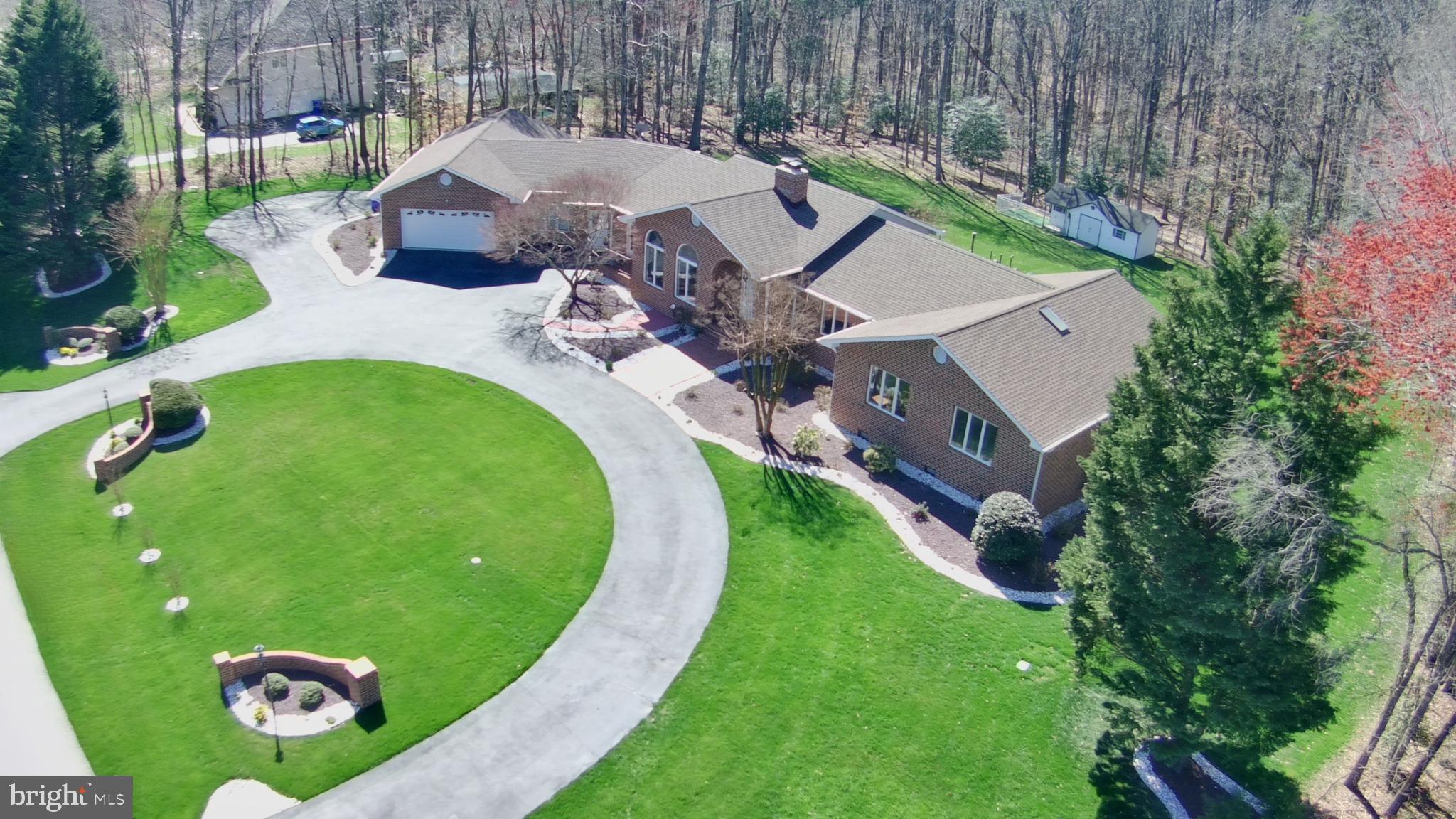 Expansive estate home on a flat 2.1 acres lot back to a wooded area in the highly desirable Locust Grove Estates! Drive up to this amazing house through the semi-circular driveway. This gem is two homes in one!
Upstairs, you will find everything you need for a true one-level living lifestyle.
The left wing of the main level features a gourmet kitchen with granite countertops, luxury tiles backsplash, stainless steel appliances, recessed lighting, a large pantry, and a breakfast area. The laundry room with a granite counter and a utility sink is off to the side of the kitchen. A full bathroom, a mudroom with exit to the back deck, a multipurpose room (great space for a play area, an exercise room, or a studio), and access to the garage round out the left wing.
The center area of the main level features the foyer, a living room, a dining room, a home office, and a lower-level recreation room. The formal dining room is large and well-lit with floor-to-ceiling Palladian Arch windows – plenty of room for family and friends. The family room features a gas brick fireplace with a custom wood mantle and a wall of windows overlooking the expansive and beautifully landscaped yard. The home office with a vaulted ceiling features custom-built bookshelves and a desk. The lower-level recreation room features a spacious and versatile room where you can set up a bar to go along with the fireplace and walk out to the outdoor patio and backyard.
The right wing of the main level is where you will find the master bedroom with a vaulted ceiling, two closets, an updated ensuite bath with double vanity with granite countertops, and a large tiled shower with a glass door. Two additional generously-sized bedrooms and an updated full bath round out the bedroom wing.
The lower level of the left wing is set up as a separate apartment – perfect for guests or an in-law suite. This space features a renovated kitchen with white cabinets, subway tile, new appliances, a dining area, a family room, a bedroom with a walk-in closet, and even its own laundry room. It has its own separate walk-out entrance.
Additionally, there are several multi-purpose finished rooms/areas for hobbies, a workshop, or storage.
An attached garage offers generous space for 2 cars, storage, and a workbench. A second oversized garage with a wall-mounted AC unit fits 2 compact-size cars and can store your boat or RV, or can be used as a large workshop. You can also park up to 7 cars on the driveway and parking pad.
The backyard is a true retreat with lush green grass surrounded by mature trees with an invisible pet fence. There are so many outdoor spaces that you can enjoy, such as the deck from the main level, the patio off the recreation room and the apartment, the fire pit area, and the playground/tree house area. The yard also features a charming shed with a dog run that includes artificial turf and pea gravel. Plenty of room to entertain your family and guests.
The property is only a 5-minute drive to downtown La Plata or a 15-minute drive to downtown Waldorf for dining and shopping. Nearby attractions include Captain Billy’s Seafood Restaurant, the Port Tobacco Marina and Restaurant, where Live Bands are featured, and a 30 min drive to Colonial Beach.
