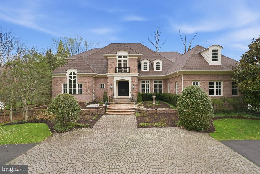 Situated on a private, one-acre lot in the coveted Langley Forest neighborhood, 904 Mackall Avenue is a substantial McLean estate offering approximately 9,100 finished square feet across three well-designed levels. Thoughtfully planned for both grand entertaining and everyday living, the home features six bedrooms (five on the upper level and opportunity for a main level primary or guest suite), five full baths, two half baths, two laundry rooms, four fireplaces, a three-car garage, and an elevator servicing all levels.

A welcoming two-story foyer with a sweeping curved staircase introduces the home’s light-filled interiors, highlighted by 10-foot ceilings, and substantial millwork throughout the main level. Formal spaces are well balanced, including a gracious dining room and a sunken living room with a masonry fireplace and Juliet balcony.

Two distinct main-level office/library spaces provide exceptional flexibility. A front-facing sunroom with soaring ceilings functions beautifully as a sitting room or workspace, while a separate library/guest suite includes a walk-in closet and full five piece bath—ideal for main-level living or private guest accommodations.

The heart of the home unfolds across the rear, where a spacious family room with fireplace opens seamlessly to the kitchen and breakfast area. A large center island, walk-in pantry, butler’s bar, and direct access to a balconey with a gas grill create an ideal environment for both daily living and entertaining. A secondary rear staircase, mudroom, and main-level laundry add convenience and functionality.

Upstairs, the primary suite is a true retreat, featuring a fireplace, tray ceiling, expansive dressing room, dual walk-in closets, and a spa-inspired bath. Four additional bedrooms are generously sized and well arranged, with a combination of en suite and adjoining baths, as well as a second upper-level laundry room. The open-to-foyer design enhances light and architectural interest.

The walk-out lower level is designed for recreation and wellness, anchored by a rare indoor exercise pool. Additional highlights include a large recreation room with a fireplace, home theater, a sixth bedroom with full bath, and multiple unfinished storage/utility areas offering flexibility for future customization.

Outdoor living is equally compelling, with multiple balconies and entertaining spaces overlooking the private, landscaped grounds. The three-car garage and elevator access to all levels further enhance ease of living.

Ideally located just minutes from downtown McLean, Tysons, and Washington, DC, this offering presents a rare opportunity to own a well-scaled, amenity-rich residence in one of the area’s most sought-after neighborhoods.