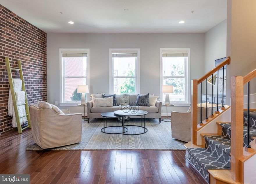 Fabulous, bright and spacious Potomac Yard townhome! You don't want to miss this former model home with  hardwood floors and many other upgrades throughout. Featuring three bedrooms, three full bathrooms and two half baths, and a dedicated home office, this home has all the space you need with every update you want. Enter the main level into the foyer and you will find a bright and sunny office with French doors. This space could easily be used as a main level bedroom, gym or playroom and has a half bath off the hallway for convenience. To the rear of the home is a two car garage with loads of storage. When you head up the stairs prepare to be amazed. A large, exposed brick wall greets you to this open area that boasts a spacious living room with oversized windows, great dining room with updated lighting and a gourmet kitchen with wine refrigerator, plentiful storage and upgraded cabinetry, gas range, stainless appliances, wall oven, quartz counters. The patio just off the kitchen is a convenient area for grilling or just getting some fresh air. A half bathroom rounds out this level, which is truly ideal for entertaining or everyday living! Head upstairs and you will find three bedrooms, two full bathrooms and a conveniently located laundry area. Two bedrooms share a gorgeously updated hall bath with soaking tub, carrara marble tiling, updated lighting and spectacular finishes. The primary bedroom features two large windows, a walk-in closet with Elfa storage and an en-suite bath with oversized shower. The upper level is not one to be missed! This area can be used as a bedroom, recreation room or entertaining space. Another wall with exposed brick makes this room feel warm and inviting, but modern at the same time. This level includes a wet bar area with beverage fridge, full bathroom, large recreation room, tons of storage and a fabulous upper deck overlooking the city.  Enjoy fantastic views of the fireworks from the deck on July 4th! The double sided fireplace will keep you warm on cool nights, whether you're hosting friends outside on the patio or getting cozy inside for movie night. From top to bottom, this four story townhouse has everything you've been looking for in a home. The Potomac Yard location cannot be beat - blocks to Del Ray, steps to Amazon's new HQ2 and the new Metro, close to Old Town, minutes to Reagan National Airport and a breezy commute into DC! Don't wait to see this beauty - it's truly spectacular! Welcome home!