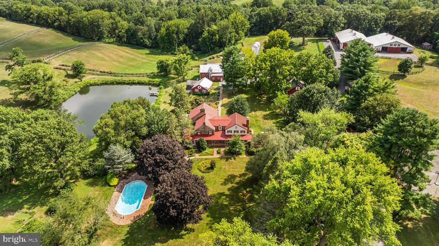 A tree-lined estate drive from Nicodemus Road gives way to bright sunlight and beautifully maintained pastures and fenced paddocks leading to the core of the 90-acre historic Rich Meadow Farm. This amazing equestrian facility is anchored by an 18th century stone farmhouse seamlessly expanded through the years and beautifully updated, set amidst lush gardens and professional landscaping. A 2-story Foyer with rustic stone and wood paneled walls sets the tone for this remarkable 5 Bedroom, 4 Bath home.  An expansive Family Room with beamed ceiling, woodburning fireplace and wet bar, cherry Kitchen opening to formal Dining Room radiate from the Foyer. A bright and sunny 35-foot Breakfast/Morning Room has access to the 2-level Deck and the vaulted Sunroom with flagstone floor. Original to the 18th century farmhouse are the Living Room and Office- both with fireplaces- and the back Foyer, the original entrance hall, all with deep-set windows and wide-plank vintage flooring. An expansive Primary Suite, 4 additional Bedrooms and 2 Baths share the upper level. Enjoy alfresco dining on quiet evenings on the Deck overlooking the pond or a refreshing dip in the heated in-ground pool. There is a separate Office or Guest House with a screened porch and deck overlooking the pond. There are 2 large barn complexes that include a total of 35 horse stalls, bank barn with 2 silos, tremendous tractor/machine shed with workshop, tack rooms, wash stall and 2 modern 2-bedroom apartments. The farm boasts 13 fenced watered paddocks, fenced riding ring, run-in sheds and a chicken coop. All beautifully maintained, eagerly awaiting new stewardship.