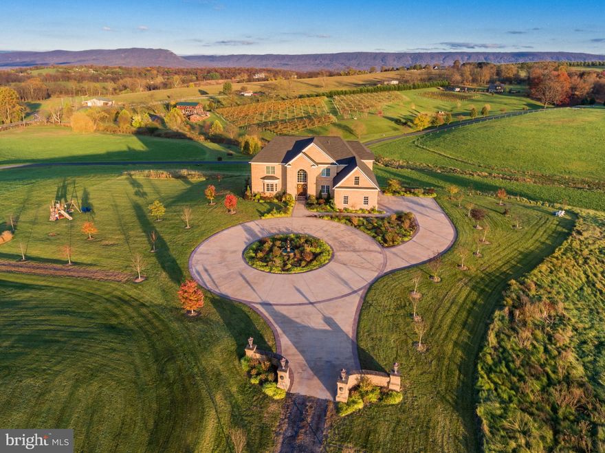 Exceptional Opportunity and Rare Find in this custom builder's dream home with over 1.5M invested**Set on nine verdant acres with breathtaking mountain views of the Shenandoah Valley, this picturesque neo-Colonial estate is a custom masterwork crafted to exacting detail in 2014. Experience a pristine blend of timeless elegance and modern comfort across an expansive floor plan of over 10,000 sq ft, including four beds and three full baths upstairs, a legal fifth bedroom on the lower level, and and one half bath on the main floor. A private drive entreats you up to the 3-car side-load garage and grand circular carpark for 10+, where visitors are met with idyllic vistas over Third Hill Winery and the surrounding landscape. Just inside, a grand two-story foyer showcases luxury tile floors and beautiful wrought-iron filigree up the graceful spiral staircase. A landing overlooks the majestic family room swimming in natural light and adorned by tray ceilings and opulent moldings, custom chandeliers and an intimate fireplace. Exquisite hardwood floors begin in the formal living and dining rooms near the entry and flow throughout the entire main floor. Entertaining is a dream in this open-concept floor plan, with an effortless transition to the gourmet kitchen featuring beautiful granite counters, high-end stainless appliances, wine fridge, and a huge two-level island with bar seating. A brilliant sunroom covered in windows offers gorgeous views of wide-open range and rolling hills. The main level is completed by an office with deck access and ornate built-in bookshelves, a powder room, and a mudroom off the garage. Upstairs, four spacious bedrooms each feature an en-suite bathroom. The lavish master suite is the height of luxury, displaying a cozy fireplace, elegant crown molding and tray ceiling, and a sitting area leading to a private balcony with spectacular views. The stunning master bath boasts a huge granite-tiled double shower, twin vanities with granite counters, and a soothing spa tub. The master bath opens to a colossal master closet, your own hidden oasis in the home. On the walk-out lower level, enjoy a fully finished and massive great room with recessed lighting, bar area, natural light from numerous windows, and French doors to the patio. The lower level also features a dedicated theater room with tiered seating levels, a fitness room, and a full bathroom. Step outside onto the expansive deck for al fresco dining with friends and family, or simply enjoy morning coffee or afternoon wine while you revel in the glorious splendor of your surroundings. With wide-open spaces and freedom to roam, only a short drive to shopping, dining, wineries and all the finest that Northern Virginia has to offer, this decadent yet comfortable estate has it all! **Included in the sale is an adjacent 4.6 acres of land to continue to build and customize your estate, Tax ID 098 06 008. Don't miss this amazing opportunity!