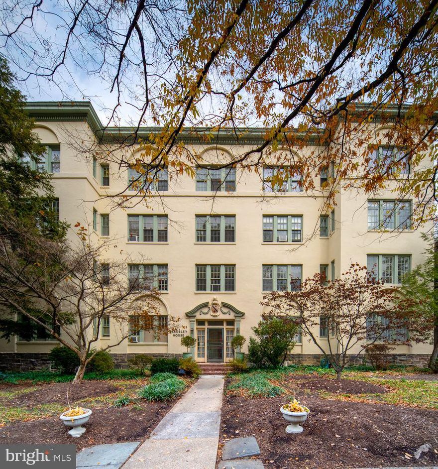 Tucked beneath one of Baltimore’s most beautiful mature tree canopies, Berkeley House stands with the quiet elegance of a 1920s architectural gem—stucco façade, classical detailing, and large multi-pane windows designed to fill each home with natural light. Set in the heart of Tuscany-Canterbury, Unit 2A is a rare residence where history, sunlight, and everyday ease come together just steps from Johns Hopkins, Wyman Park, and the best of north-Baltimore living. Inside, the scale and character of pre-war architecture immediately stand out: soaring ceilings, wide hallways with rich millwork, arched doorways, and the warm glow of 28 restored original windows. With south, east, and west exposures, the home is bright from morning to sunset, offering calming treetop and courtyard views throughout. The gracious living room features original hardwood floors, a decorative fireplace, and a sweeping arched opening into the formal dining room—a window-lined space ideal for entertaining. A corner sunroom, surrounded on all sides by glass, makes a wonderful home office, creative studio, TV room, or potential third bedroom. The kitchen blends classic charm and functionality with tile floors and rich green cabinetry. Two large bedrooms anchor the private wing, each with its own full bath.  Thoughtful updates throughout respect the home’s architectural integrity: preserved hardware, plaster archways, period moldings, and soft, sophisticated color palettes. Berkeley House offers the feel of a private, residential enclave with only eight units, landscaped grounds, and a fenced backyard garden shared by the building. Unit 2A includes a private garage plus two additional outdoor parking spaces—a rare advantage in this highly walkable neighborhood. 
Unmatched location + lifestyle: • Johns Hopkins Homewood Campus – 2 blocks • Wyman Park – steps away for strolls, jogging, picnics, and wooded paths • Baltimore Museum of Art & Sculpture Garden – 5 minutes • Sherwood Gardens, Loyola, Union Memorial, The Rotunda – all nearby • Neighborhood cafés, culture & convenience: Enjoy coffee at Bird in Hand or On the Hill Café, brunch at Gertrude’s, evenings at Guilford Hall Brewery, and easy access to Charles Village shops, bookstores, and restaurants. Tuscany-Canterbury is known for its peaceful, tree-lined streets, historic architecture, and exceptional walkability. Berkeley House 2A is a home with character, warmth, and history—wrapped in the rare combination of green space, culture, and convenience. A uniquely warm and connected place to call home.