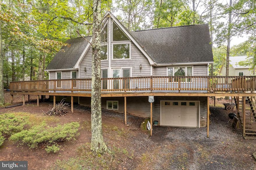 Spacious Chalet in exclusive gated LAKE community close to Winchester! Wonderfully priced for a golden opportunity to make this gem your own with a few modern updates. Over 2400 finished square feet, this cozy home has what you’re looking for with a main level owner suite, large adjoining bath and 2 story living room offering a ton of light! 3 additional ample sized bedrooms upstairs. Finished basement with large brick center makes a perfect great room on a walk out level. Extensive wrap around deck and lower-level garage. Solid home and part of an estate so being sold as is; prefer conventional financing due to cosmetic updating needed.