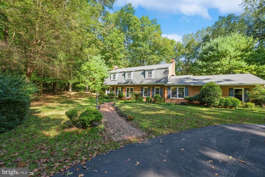 HUGE PRICE ADJUSTMENT**An Excellent Opportunity to own this handsome 5 BR/3.5BA  brick colonial is sited on a fabulous  cul-de-sac lot in secluded wooded setting in sought after English Hills, one of Fairfax Station's most beautiful equestrian neighborhoods.  Spacious rooms with hardwood flooring throughout main and second floors. Main level features double door foyer entry; spacious formal living room with brick wood burning fireplace;  dining room with built in corner cupboard and beautiful bay window with stunning view of woods; a large family room with full brick wall fireplace and wood box,timbered ceiling, and a wall of built in bookshelves and cabinets, Kitchen with eat-in dining space, pantry, cooktop, wall oven, refrigerator, built in microwave ,dishwasher, lots of counter space and wood cabinets. Upstairs to the bedroom level with four good sized bedrooms and two full baths, window seats in three of the bedrooms add to the charm of this home. The walkout lower level has ample space for all, a recreation room (even has a dance floor to get your disco on), fireplace with wood stove, party bar with built ins, a 5th bedroom and exercise /den/or movie room , laundry room  plus an additional full bath  HVAC  system is a heat pump with oil backup for heating (above ground tank) Enjoy peaceful evenings and cool afternoons on your spacious deck with views of trees, trees and more trees. This extraordinary, private nearly five acre estate features circular driveway allowing for easy entrance and exit to home,  extensive landscaping, brick walkways, mature trees and abundant wildlife. Living in Fairfax Station, you will enjoy the solitude of the Virginia Countryside, yet you are just minutes from many conveniences of the nearby suburban areas. This ideal location is just a short drive for any easy commute via Fairfax County Parkway or the Virginia Railway Express. Close by is the historic town on Clifton featuring fine and casual dining, boutique shops and parks. Burke Lake Park is minutes away where you can enjoy a round of golf, a paddle boat, Frisbee golf or a hike around the lake. Recent updates in 2023 new roof and gutters, fresh exterior and interior paint, and updated light fixtures. WELCOME HOME WE THINK YOU WILL WANT TO STAY.