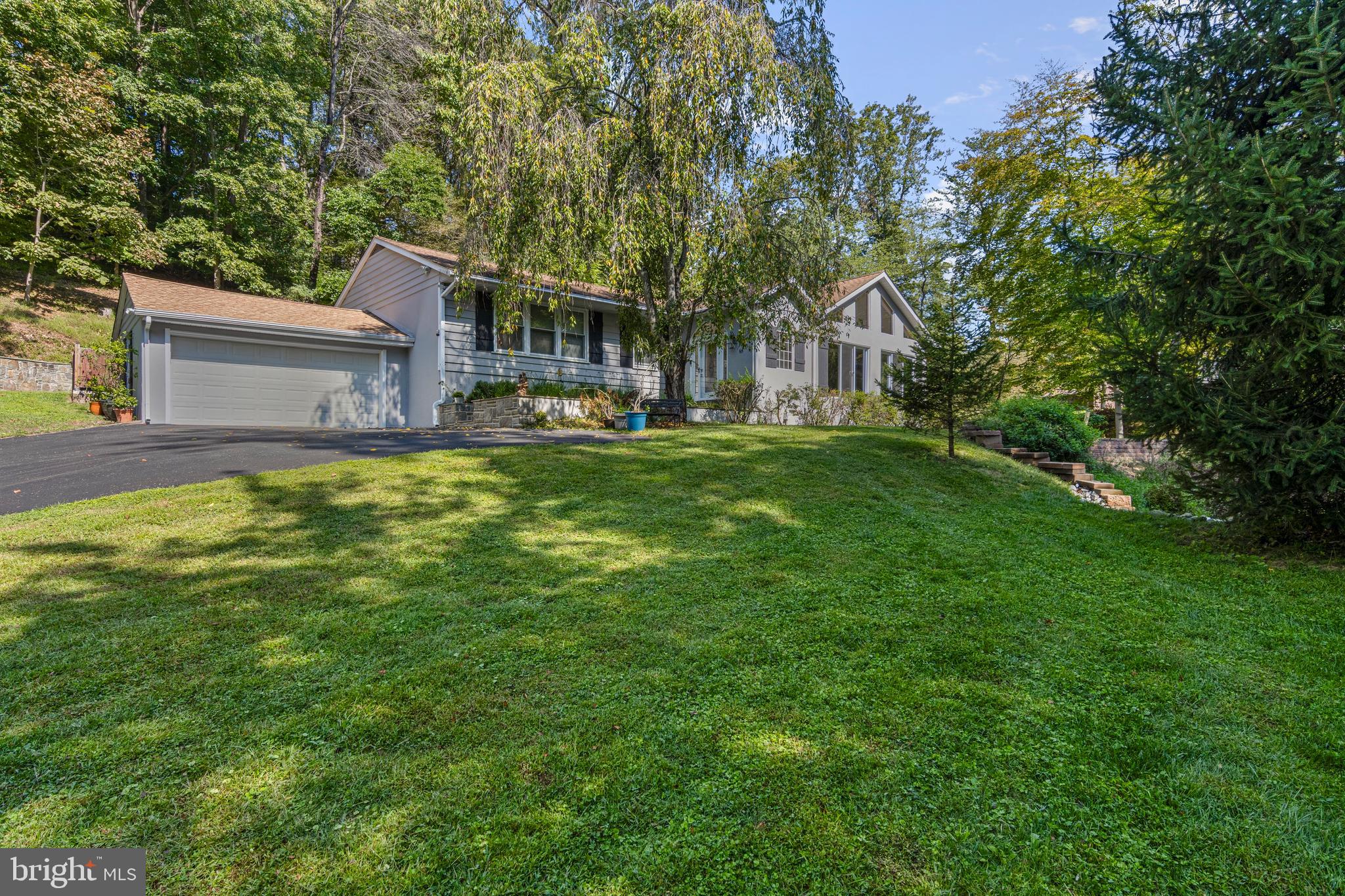 Welcome to your private retreat in Glen Mills — a rare hidden gem that blends luxury, privacy, and functionality. Enter through the double-gated driveway, past the serene fish pond and fountain, into a natural paradise bordered by 150 acres of wetland preservation and 25 acres of historic preservation. This one-of-a-kind property sits on over 7 acres in the award-winning Garnet Valley School District, just minutes from shopping, dining, major routes, and the airport. The main residence offers more than 3,500 sq. ft. of living space. A welcoming foyer opens to a dramatic sunken living room with soaring 15’ cathedral ceilings, a floor-to-ceiling stone fireplace with wood-burning insert, custom black walnut shelving, dual fans, skylights, and abundant natural light. French doors lead to an entertainment room with vaulted transom windows, the perfect spot to enjoy wildlife and a natural spring. At the heart of the home is the chef’s kitchen, featuring custom cabinetry, upgraded appliances, a built-in workstation, and an expansive two-tier granite island with 13’ of counter space. An attached sunroom/greenhouse provides a bright sitting area or year-round growing space. The private primary suite showcases floor-to-ceiling windows, dual walk-in closets, and a spa-inspired en-suite with heated travertine floors, Jacuzzi tub, and multi-spray digital shower. Three additional bedrooms with oversized closets (one cedar) and a beautifully renovated hall bath complete the opposite wing of this amazing 1 story rancher. A finished half-basement with new carpet, a dry bar, and ample storage connects to the oversized two-car garage, which features a mechanics pit for car enthusiasts. Outside, enjoy the expansive stamped-concrete patio and separate firepit area ideal for entertaining. A natural spring flows into a babbling brook with three custom bridges and a hand-built retaining wall adds to the property’s charm. A major highlight is the 2,300 sq. ft. heated Class C building with half bath, currently used as a business workshop. This versatile space offers endless potential — from a car collector’s dream to guest quarters. A covered exterior area provides storage for equipment and firewood, while a fully floored and insulated attic expands capacity. Additional upgrades include a wood-burning system that heats both the shop and the entire home with portions of the home having radiant heat floors, whole house & 2nd building backup generator, newer roofs on both structures, energy-efficient windows, new driveway and fencing with dual entry gates, and plentiful parking for large gatherings. Amazing wildlife. Bow Hunting allowed on the property. New Septic system (2021) This is a 100% turnkey property. This remarkable property combines privacy, luxury, and functionality — offering the best of country living with easy access to modern amenities. Your home will be the talk of everyone who visits. All of this in the highly desired school district of Garnet Valley. Minutes to all major routes, plenty of shopping and dining options. *Other items possibly available with the property for purchase include an upgraded golf cart, a top-tier quad vehicle, three riding mowers, a log splitter, a mini backhoe, chainsaws and much more. You simply must see this property in person. If interested, a private tour of the entire grounds with the owner can be arranged. * Seller may include items at sellers discretion. **Seller may credit the buyer to have the second driveway resurfaced