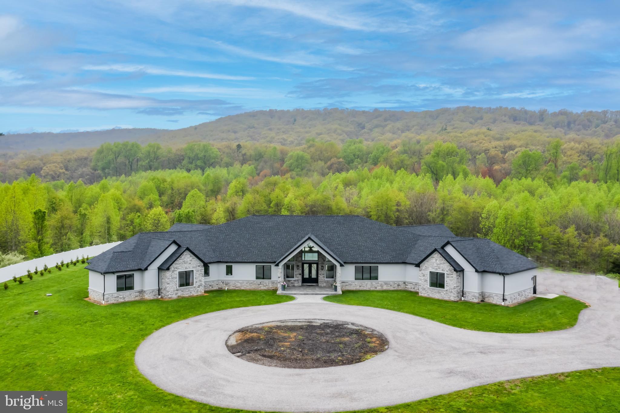 This tastefully designed, expansive stone and drivit contemporary ranch home, perfectly situated on 11 acres, built by Bretstin Builders, is truly the perfect place to call Home! From the moment you enter, you'll experience the bright and open floor plan. Carefully selected architectural design elements and finishes include gorgeous white oak plank flooring throughout the home with extra wide hallways. Cathedral ceilings accent several rooms. The gourmet Kitchen will be sure to please the culinary enthusiast. Kitchen features expansive island with quartz counters, pop-up outlet, tile backsplash, a 6-burner Wolf range with center griddle and dedicated pot-filler spigot, two dishwashers, Sub-Zero refrigerator, two in-island refrigerator drawers, two sinks, spacious walk-in Pantry, and beverage center with wine refrigerator. Owner's retreat offers a spa-like bath featuring dual vanities with vessel sinks, custom tiled 2-person shower, private water closet, free-standing vessel soaking tub, spacious customized walk-in closet with Safe Room. French doors from the owner's retreat lead to the outdoor patio and pool area. This 5-bedroom home also features two ensuite bedrooms, and two bedrooms sharing a jack-n-jill bath with separate toilets and vanities for each bedroom. A Laundry Room complete with sink and storage cabinets as well as a private Study/Playroom/Craft Room are conveniently located to the bedroom wing of the home. Finishing the inside of the home are a delightful Sunroom overlooking the rear yard and Den with cathedral ceiling. Adjacent to the Kitchen are the Family Room and Living Room both with gas fireplaces flanked in beautiful marble tile as well as a spacious Dining Room with vaulted ceiling. Two 1/2 baths. Convenient "drop zone" near the entrance to the garage. Small pet room adjacent to drop zone with access to fenced dog run with artificial turf. Complementing this magnificent home is a spectacular rear outdoor fenced area, perfect for relaxing or entertaining with a 30' x 50' heated in-ground saltwater pool with electric retractable cover and concrete decking. Propane fire pit. Accessible from the patio area, without entering the home, is a full-tiled bath which is perfect while entertaining and for pool parties. Provisions were made during construction of the home for a hot tub to be added just exterior to the owner's retreat as well as a future outdoor Kitchen area, and rough-in plumbing for pool house bath. The finished, over-sized, 3-car garage and unfinished basement provide abundant storage. Dual fuel HVAC systems provide zoned heating & cooling, two hot water heaters, water treatment system, security system and so much more! Experience this exceptional home today - you'll be glad you did!