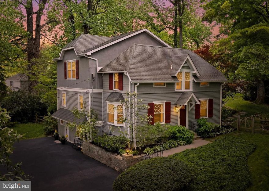 Tucked away in the heart of Villanova, 211 Comrie Drive is a garden retreat unlike anything else on the market. Originally a carriage house on the Hardwicke Estate, this one-of-a-kind home has been thoughtfully reimagined with 5 bedrooms, 3 full baths, several versatile bonus rooms, and over 3,700 square feet. A long private driveway leads to a generous parking area with room for 6+ cars, setting the tone for a home that is both charming and highly functional. Inside, the main level offers an updated kitchen with rich wood cabinetry, a large center island, stainless steel appliances, and easy connection to the dining and living areas. The standout family room is wrapped in diamond-pane windows, framed by a dramatic 15-foot tray ceiling, and opens through French doors to the rear garden. A bedroom, full bath, laundry, and an additional room currently used as an office add flexibility for guests, work, or everyday life. Upstairs, four additional bedrooms include a comfortable primary suite with walk-in closet and double-vanity bath, along with well-sized secondary bedrooms and additional full baths. The lower level extends the home’s versatility with a finished recreation room, large mudroom with built-ins, and generous storage. The outdoor setting is the soul of the property: fully fenced and surrounded by mature trees, layered landscaping, stone walls, open lawn, and tiered patios, the rear yard feels like a lush escape designed for quiet mornings, summer dinners, entertaining, and play. Set along a quiet Radnor Township street close to The Agnes Irwin School, Villanova University, and the conveniences of the Main Line, 211 Comrie Drive offers estate history, modern livability, and a rare sense of seclusion in a truly special Villanova setting.