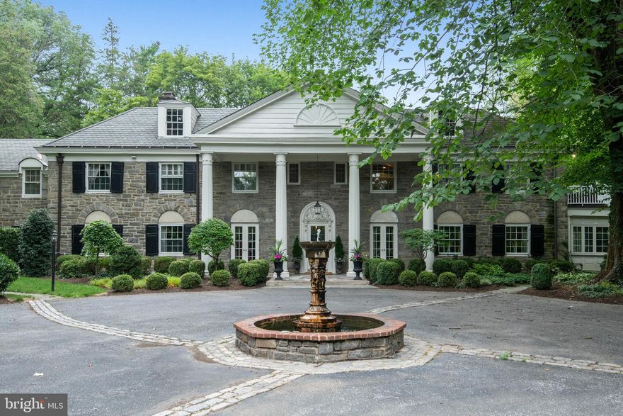 This Stunning Merion Golf Manor Estate embraces the rich architectural heritage of the Main Line. Meticulously and tastefully renovated to complement today's lifestyle, completed to the highest standards of the most discerning buyer. Offering high ceilings, walls of windows, and spectacular architectural details, the perfect marriage of luxurious renovations and original grandeur.  A circular driveway with a whimsical fountain draws you to the columned entry of this Classic Stone Main Line Estate. Enter into an expansive and grand reception hall with a dramatic staircase. Beyond the center hall with a formal powder room, is the expansive living room with large windows and classic deep window sills, a fireplace with elegant marble surround, the perfect space to entertain in.  Off of the living room is a sunroom overlooking the grounds with a fireplace, this space is currently a home office. Sliding barn doors lead you to the cozy family room with gas fireplace and custom built-ins creating the perfect place to relax or cozy up with a book. A Grand Formal Dining room also features an original marble surround fireplace and floor to ceiling windows and can accommodate large dinner parties. The show stopping Chef’s kitchen offers an intelligent design, eye catching designer accents and sumptuous finishes. The large seated island with Arabesque Marble Counter accommodates not only seating for five but a prep sink, GE profile refrigerator drawers, warming drawer, and ample cabinet storage. To name a few of the highlights the kitchen is graced with a 60 inch Wolf Dual Fuel Range, a 30” Subzero refrigerator, custom white cabinetry, two sinks for easy clean up - each with its own adjacent dishwasher and an ice maker in the beverage center. The kitchen has exposed beams in 3 places, a nod to the home's history, a stone accent wall with encased gas fireplace keeping it cozy all through the winter! A walk-in pantry, and a table with built-in bench seat for casual dining complete the space. Conveniently the kitchen is accessed by the second staircase leading you to the En Suite apartment above and offers access to the 3 car garage with 3 Tesla chargers. Off the kitchen a mudroom leads you to a breezeway with outdoor access to the powder room, and the expansive flagstone patio, the perfect place to enjoy outdoor dining or a coffee overlooking the grounds and gardens.  Ascend the stunning staircase to the Primary Suite, truly a retreat, with marble surround fireplace, private balcony overlooking the grounds and an excellent vantage point of the tennis court, a large custom outfitted walk-in closet, and a luxurious spa-like bath. Recently completed, the Bath has a Copper Soaking Tub with jets that allows for two adults to fully submerge. Beautiful Ashford Carrara marble envelopes the bathroom and radiant heated floor, the hammered copper sinks complement the soaking tub, and the designer fixtures accent the bath and marble shower. Down the hall there are three en-suite bedrooms each with tastefully renovated designer bathrooms. A fifth bedroom is served by a full bath with a soaking tub accessed down the hallway.  A fully renovated and self-contained apartment has its own kitchen, laundry rm, living rm, bed rm, and full bathroom, the perfect space for in-laws, or nanny suite with separate outdoor access. The Lower Level was recently fully renovated and offers a fireplace, a large screen TV projector perfect for movie night, a wood-finished wine room, powder room, and exercise room with rubber gym floor, and an additional storage space to complete the lower level. The over 2 acres of ground envelopes the Estate in privacy and the lighted tennis court delights in the spring, summer and fall months. There is a private gate that exits to Blakely for access for leisurely walks. This home also includes a central vac, tankless water heater, three zone HVAC, and surround sound. In the Heart of the Main Line & convenient to Philadelphia.