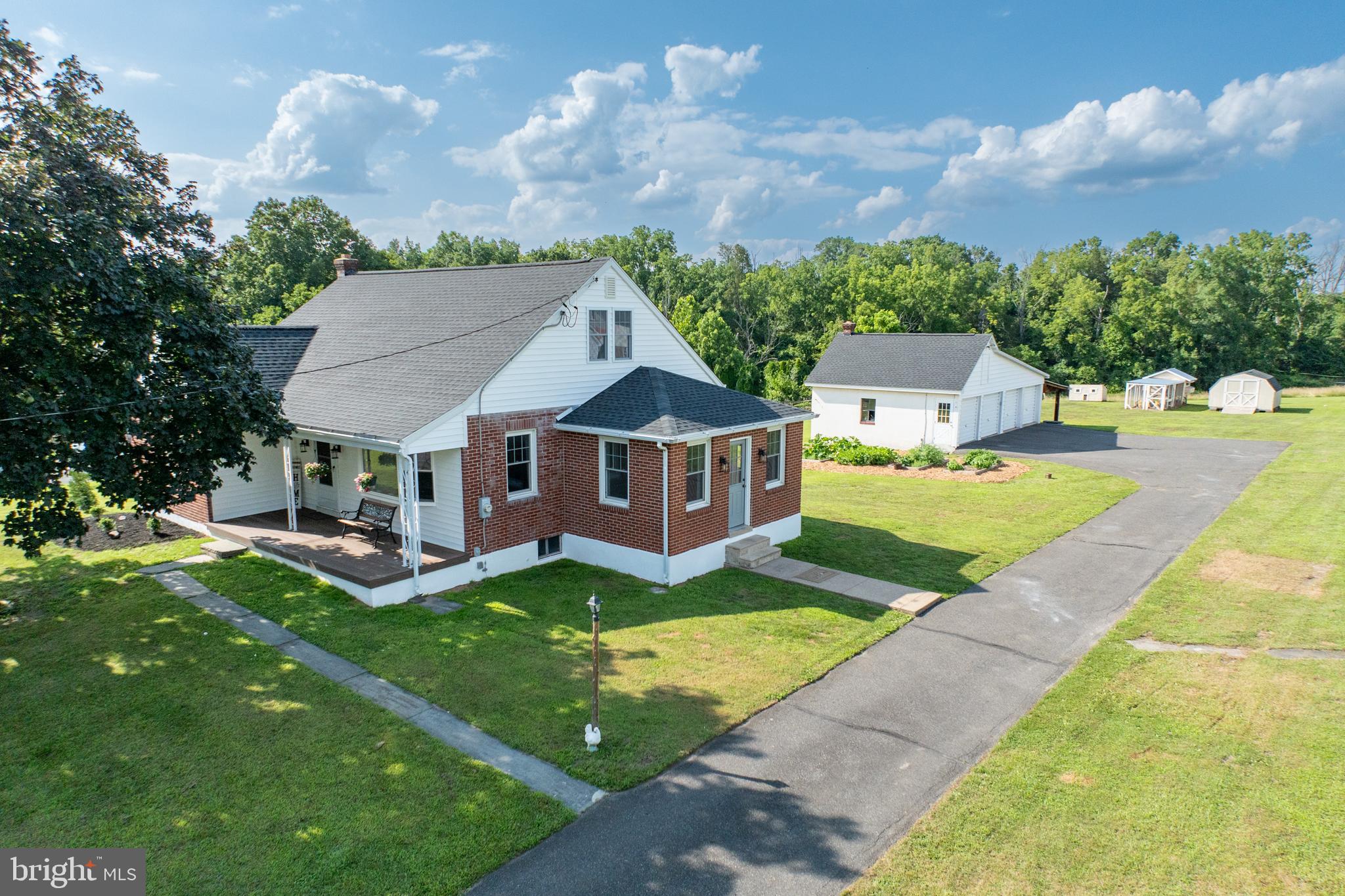 Friendly and inviting! This 4-bedroom brick Cape Cod offers the perfect blend of country character and practical updates—set on a generous lot with a dream garage setup for hobbyists, collectors, or anyone needing serious storage. A rare find, the detached 4-car garage features a water spigot, a hydrant in one bay, automatic garage door openers, and plenty of space for vehicles, tools, or recreational toys. An extended overhang with a concrete floor adds even more covered outdoor space. Plenty of driveway space. For those who love a touch of homesteading, there’s a chicken coop and shed—both equipped with lights and outlets.
Inside, the home greets you with an expansive mudroom featuring a cathedral ceiling and new vinyl flooring. This versatile space can serve as a sunroom, bonus entry area, or even a home gym. The kitchen has been tastefully refreshed with white painted cabinetry, new butcher block countertops, a glass-top electric oven, dishwasher, refrigerator, ceiling fan, and a sweet coffee bar area with floating shelves for display and storage.
The living room is light and welcoming with neutral carpet, a large bay window, and ceiling fan. On the main level, the primary bedroom offers hardwood floors, a ceiling fan, and a spacious closet. A second bedroom on the first floor makes an ideal office or guest space. The full bath has been updated with a tile floor, a large white vanity with quartz top, a new toilet, and a tub with stylish glass tile surround and a rain-style showerhead.
Upstairs are two additional bedrooms, including one with a cedar closet. The full basement adds even more value with a root cellar—perfect for canning, wine storage, or pantry overflow—alongside a washer and dryer area, bilco door, a wood stove, and an oil furnace (2016). This home has the advantage of 2 heat sources, forced air and oil. A whole house fan helps keep things cool in warmer months, and the home has been fully insulated with blown-in insulation for energy efficiency. Newer electrical wiring.
Enjoy outdoor time on the covered front patio, and appreciate the privacy and space this property offers—all while being close to amenities. Whether you need room to grow, space to work, or a place to play, this home checks all the boxes.