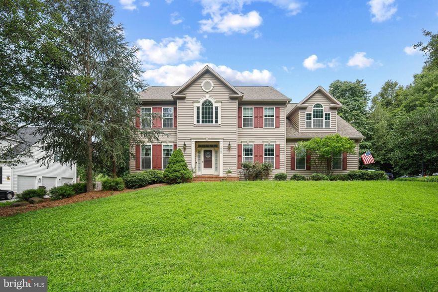 Welcome to 2802 Apple Cinnamon Place, nestled in the highly sought-after and rarely available Gingerville Woods community. This beautiful home offers privacy on a one-acre lot backing to serene forest, providing a peaceful retreat while enjoying easy access to Route 50/97 and the city of Annapolis. Step inside to a stunning two-story foyer featuring elegant interior columns, a double staircase, and gleaming hardwood floors that flow through the living and dining room and into the spacious open kitchen. The kitchen boasts solid wood cabinets, quartz countertops, a tile backsplash, and a center island, opening to a bright breakfast area and a sunken family room with a warm propane gas fireplace.  A convenient mudroom with washer, dryer, utility sink, and built-in shelving connects the kitchen to the three-car side entry garage.  Enjoy outdoor living on the large screened porch and deck overlooking the private backyard with a fire pit and wooded views. Upstairs, find five spacious bedrooms, including one with a soaring cathedral ceiling, and three full bathrooms. The finished basement features a large recreation area, an additional room, storage area and a sliding  French door leading to the backyard. Additional highlights include a new roof, whole-house generator, and two-zone HVAC. Don’t miss this opportunity to call Gingerville Woods home—schedule your showing today!