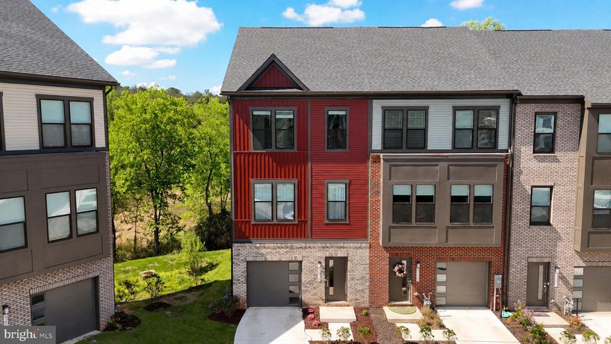Welcome to an extraordinary 2024-built luxury end-of-group residence nestled within the highly coveted Watershed community in Laurel, MD—where refined design, elevated finishes, and a private wooded backdrop converge to create an experience that feels more like a retreat than a townhome. From the moment of arrival, the striking red vinyl exterior accented by a timeless brick water table, expansive three-car driveway, and front-loading garage establish an undeniable sense of presence, while the premium end-unit positioning introduces an abundance of natural light and rare privacy throughout. Inside, sun-drenched interiors unfold across meticulously curated living spaces enhanced by luxury vinyl plank flooring, regal molding details, custom window treatments, and a calming designer palette that radiates sophistication. The heart of the home is a stunning chef’s kitchen thoughtfully designed for both everyday luxury and elevated entertaining, featuring a gas-powered gourmet layout with stainless steel appliances, dazzling Calacatta quartz countertops, deep stainless steel sink perfectly positioned beneath picturesque windows overlooking the trees, crisp 42” Snow White cabinetry, white subway tile backsplash, and exquisite gold hardware that ties the entire space together with effortless elegance. Flowing seamlessly from the kitchen, the expansive dining and family room areas are wrapped in walls of windows exclusive to end-unit living, flooding the home with natural sunlight and creating a warm, airy ambiance throughout the main level. Ascend the white oak hardwood staircase into a true owner’s retreat where luxury continues with refined molding accents, neutral designer tones, dual walk-in closets, and a spa-inspired ensuite bath boasting double vanities, Calacatta quartz countertops, tiled flooring, neutral cabinetry, and a frameless glass shower complete with built-in seating for a serene retreat-like experience. Two additional upper-level bedrooms showcase stylish accent walls, custom treatments, and a beautifully appointed secondary bath featuring quartz surfaces and designer tile surrounding the tub/shower combination. The lower level offers remarkable versatility with an expansive fourth bedroom, full upgraded bathroom, luxury flooring, garage access, and direct walkout access to the backyard oasis—where the covered patio beneath the TRX deck creates a peaceful setting embraced by the privacy of mature woods. Outdoor living is elevated even further with a full TRX deck and staircase connection between levels, seamlessly blending indoor and outdoor living. Located within one of Anne Arundel County’s most desirable amenity-rich communities, Watershed offers resort-style living with community pools, fitness amenities, playgrounds, walking trails, dog parks, green space, and gathering areas while being ideally positioned minutes from BWI Airport, Fort Meade, NSA, MARC train access, major commuter routes including I-95, Route 32, and Route 100, along with premier shopping, dining, and entertainment destinations. A rare opportunity to own a nearly new luxury residence that perfectly balances sophistication, convenience, privacy, and lifestyle in one of the region’s most sought-after communities.