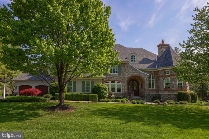Nestled on a private cul-de-sac, this stunning French Country estate was custom built in 2006 on a one-acre lot overlooking the 5th and 6th holes of the Bent Creek Country Club Golf Course. With masonry stucco and stone construction, brick accents, and a new roof added in 2023, the home offers 8,605 square feet of total living space across three floors, including seven bedrooms, six and a half bathrooms, four fireplaces, and a four-car garage with basement access. The two-story foyer welcomes you with marble flooring, a curved wrought-iron staircase, and a seven-foot crystal chandelier on a remote lift, while the family room features a coffered ceiling and a custom French 48-inch Rumford fireplace. The chef’s kitchen boasts custom cherry wood inset cabinets, granite countertops, limestone flooring, a Wolf double oven range, Sub-Zero refrigerator, two dishwashers (Miele and Fisher & Paykel), two custom islands, a walk-in pantry, and a large farmhouse sink. Additional main-level highlights include a private office with golf course views, a formal dining room with butler's pantry, a mudroom with built-in benches and a full bathroom, a library with floor to ceiling mahogany built-in bookshelves with rolling ladder & fireplace, a first-floor guest bedroom with a private full bath, a first-floor stackable washer and dryer, and a powder room with faux French-painted walls.  Upstairs, the sprawling primary suite is a luxurious private retreat, complete with a cozy fireplace, a massive dressing room anchored by a large built-in cabinetry island with marble top, and custom-designed closets that offer exceptional organization and elegance. The second floor also includes a dedicated homework/computer room, a large laundry room with a long countertop and built-in cubbies for folding and sorting clothing, and additional bedrooms that each offer custom cabinetry, generous closets, and beautifully appointed bathrooms. The lower level is designed for entertainment and wellness, featuring a gym with mirrored wall, game room, craft room with custom cabinetry and sink, a bar with granite countertops and dishwasher drawer, a family room with stone fireplace, a bedroom with full bath, and a home theater with elevated seating for twelve, plus a large unfinished storage area. From the mahogany and leaded glass front doors to the Rocky Mountain Bronze hardware and built-in sound and security systems, every detail of this property exudes timeless luxury.
