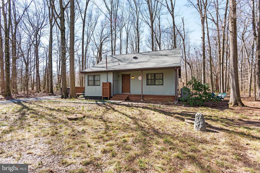 One-of-a-kind property with some unique features nestled on a wooded lot with a lovely front porch and side deck. The first floor features a large living area, kitchen, full bath, and huge utility room/office that could be converted to a bedroom if the washer and dryer were relocated.  A metal spiral staircase takes you up to a large vestibule/sitting area with a bedroom off each side.  The home is smaller but does not feel closed in. Lots of windows. Distinctive metal ceiling in the living room and other features give the property a nautical feel.  The house was gutted and rebuilt in 2007-2012. Join the voluntary civic association and enjoy the water access amenities of Chesapeake Landing.