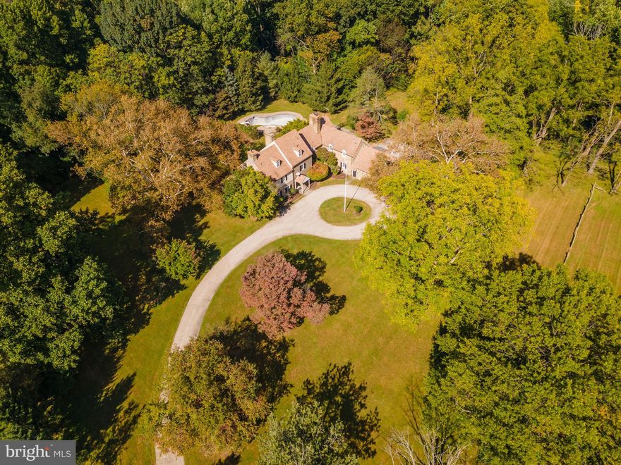 At the end of a private, tree-lined circular drive sits picturesque Chestnut Ridge Farm at 601 Spring Lane. Set on 3.39 beautiful acres, this 7 bedroom, 4 full and 1 half bath farmhouse is the perfect opportunity to customize a grand home, with in-ground pool, multiple slate terraces, and 2-car garage with separate apartment above. Fabulous original architectural details are found throughout – original iron and milk glass hardware, arched doorways, crown molding, wide plank random width hardwood floors, large fireplaces and deep windowsills. The front entrance foyer with center hall features a fireplace and leads to the spacious living room with exceptional original schist fireplace, paneled walls and arched doorway. A large dining room to the right, also with fireplace, features extensive built-ins and additional front door. A cozy room with walls of built-in shelving and cabinets could become the perfect library or work from home office. The large kitchen is built for entertaining family and friends, with extensive original glass-front cabinets, double sink, electric cooktop, double ovens, and sweet breakfast/dining area with bay window with banquette seat and original wood-burning stove. The rear of the home and 2-car garage can be accessed by the adjoining laundry area/mudroom. The second floor of this distinguished house can be accessed by two different staircases, and features 2 wings with 4 large bedrooms, 2 full baths, and the owners suite. The owners suite offers a large walk-in closet, a large sitting/dressing area, and large full bath with dual vanities and walk-in shower. The third floor offers an additional two bedrooms, and full hall bath with walk-in shower and cedar closet. A separate apartment above the garage with kitchenette and renovated new full bath could be the perfect in-law or au pair suite. Extensive slate terraces with an in-ground pool overlook the mature trees and grounds, frequented by deer, fox, hawks and more. Spring Lane is in a superlative location just minutes from the beautiful meadows of the Schuylkill River Education Center, the shopping and dining of Roxborough, Chestnut Hill and Manayunk, major roads and parks. Don’t miss this one-of-a-kind opportunity to make this special property your very own. An additional lot at 639 Spring Lane is also for sale.