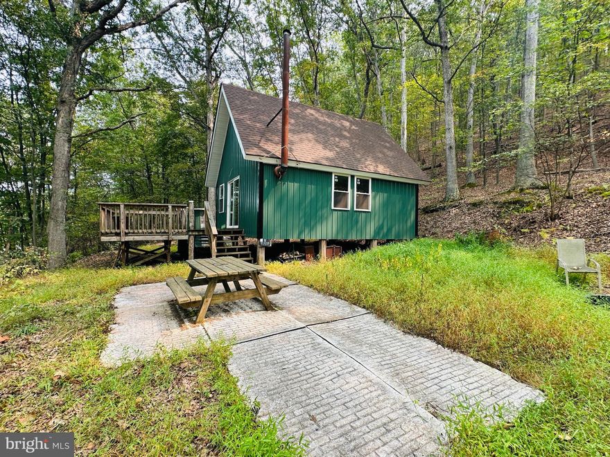 Escape to your own private retreat on just over 5 wooded acres in Great Cacapon. This unfinished mountain cabin offers the perfect opportunity to bring your vision to life. Tucked away in the trees, the setting is peaceful and secluded—ideal for a weekend getaway or full-time living once completed. The current owner has already made major improvements including regraded driveway access, new aluminum siding, plumbing rough-ins for a kitchen and bathroom, electrical wiring throughout, and spray foam insulation. The restored wood-burning stove is fully functional, creating a warm centerpiece for the home. The property has been perc-approved for a 2-bedroom septic system, though the septic has not yet been installed. With much of the groundwork complete, this property is ready for someone to finish and enjoy a cozy cabin in the mountains.