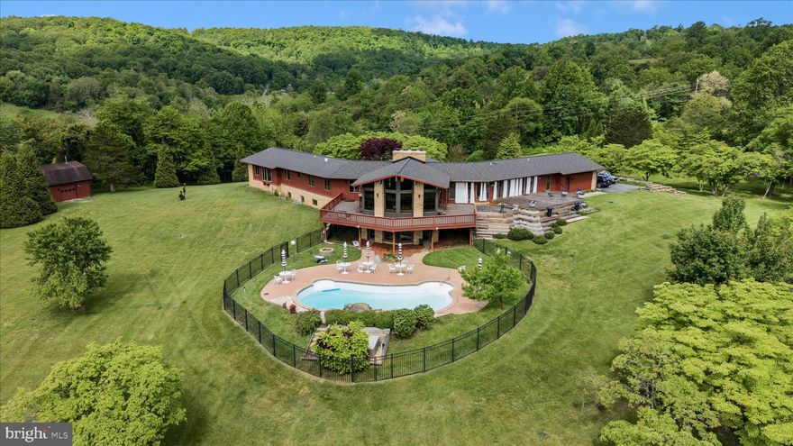 Experience the flow of space and harmony a private 5-acre sanctuary where mid-century soul meets meticulous architectural restoration. Set among park-like grounds and hundreds of flowering trees, this retreat-like residence is wrapped by protected conservation land on two sides, delivering incomparable privacy and a serene stage for entertaining, work, and retreat. From the views of Middletown Valley and South Mountain to 1960s design roots, to modern comfort, the home embodies seclusion without sacrificing accessibility.

At the heart of the living spaces, a grand fireplace anchors the flow, guiding the eye and gathering rooms into a seamless continuum. The layout invites conversations to drift from indoor to outdoor and back again, with spaces merging around this warm, sculptural anchor. From Kentucky pink sandstone and cedar exteriors to warm interior touches—wood floors, custom concrete sinks, maple doors and trim, and a well-organized mudroom and laundry area—every surface speaks to craft and longevity.

On the main level the Center Room is designed for living and entertaining. It is enriched by commissioned art, beautiful Kentucky sandstone fireplace and huge windows that look out over the Middletown Valley. A wrap around deck allows transition from the indoors to out, with just a few footsteps. 

A dedicated library with custom maple shelving creates a quiet, sunlit mezzanine of ideas—is a perfect retreat for reading, group study, or inspiration.

The stunning kitchen was designed in collaboration with local architect, Clyde Burger. The two 12’ long walnut islands and all the kitchen cabinetry is hand-built Mennonite woodwork. The work surfaces are polished concrete, and the built-in appliances are professional grade. A kitchen lounge houses built-in cabinetry and encourages family and social time as meals are prepared and enjoyed. An 18-foot NanaWall opens to dissolve the boundary between inside and outdoor.

The main level laundry has clean lines, beautiful carpentry, wonderful hand built floating shelves, custom concrete surfaces and sink as well as a wet floor and direct access to the decks and yard. The mudroom and powder room also feature custom cabinetry and specially designed features, such as the concrete sink and the floating concrete benches. 

The primary suite is un-filled, architectural artistry with an imported floor, two walk-in closets (one cedar-lined), and a bath featuring terrazzo floors and a standout view.

Two en-suite bedrooms, renovated December 2025, have wood floors with custom Navajo-inspired wood inlays. Commissioned furnishings fill of the rooms and both enjoy nature views. 

The lower-level spaces are also remarkable. The second grand room has a vibrant MCM fireplace and is ideal for family activities, mediation or intimate gatherings. The windows showcase the valley view, and the doors open directly to the saltwater pool.  Two private rooms are ready to use as bedrooms or office spaces. The full bathroom also has a custom concrete vanity and floor and warm cork tiling. This wing of the lower-level embraces angles and has built floating shelves in the lower library. 

Additionally, this level offers a bright, versatile studio providing space for creativity of all types—art, writing, design, or restorative projects— to inspire and nurture imagination. 

The exterior grounds are a living landscape. The 5-acre parcel unfolds as a natural paradise with park-like landscaping and hundreds of flowering trees seen from every window. The long drive lined with light poles and the parking area edged by planters sets a welcoming tone as you approach the home. A multi-level Brazilian hardwood deck overlooks a heated saltwater pool; a detached barn houses a traditional Scandinavian sauna and a lounge for year-round wellness.

The homes systems are wellness-oriented including geothermal HVAC, a brand-new roof with a 50-year warranty, a multi-stage water softening system.