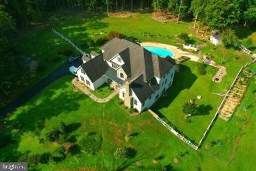 Let the summer fun begin! This amazing home is situated on 5.9+ acres, complete with a pool and spa! As you drive up the private driveway, you will appreciate how the home is situated on a knoll and love its regal appearance.  With a stucco exterior, dormer windows, a newer fence surrounding the pool area, gorgeous flagstone walkways, and a cozy front porch, you will be inviting family and friends over every weekend to enjoy this space! Step into the soaring foyer and take in the view to nearly every corner of this level. Open, light, and bright, this home welcomes you in! To the left is the formal dining room, which can easily accommodate a large table. The kitchen lies just behind the dining area for easy food service.  To the right of the foyer lies a formal living room that is just gorgeous! The wood burning stone fireplace keeps the space warm in the cooler months, while the expansive windows keep it sunny and bright - an ideal spot to catch up with friends. The two story family room is the anchor that holds the two wings of this home together, with a  stone fireplace as the focal point. Floor to ceiling windows adorn both sides of the fireplace, and the views to the pool and patio are priceless.  This will be the space where memories are created! Additional features in this room include  stone flooring inlaid in the hardwood floor, a whole house speaker system, and a ceiling fan. Veer to the left and you will find the spacious gourmet kitchen, with stainless steel appliances, granite and Corian countertops, and TONS of cabinet space. A work desk with more storage, additional space for a table, a large walk in pantry, and the laundry room round out this section. With access to the three car garage (with upgraded flooring) as well as doors to the amazing backyard oasis, this will surely be where most of your days begin and end! The main level owners' suite is like no other - two stories with huge windows overlooking the pool and patio, a two sided propane fueled fireplace, and so much space to give it your own design! The bathroom boasts a steam shower, soaking tub, double vanities, and private W/C. A separate vanity area with a large mirror, storage, and bright lights is perfect for getting ready for a busy day. The walk in closet will delight any shopper! Take the spiral, wrought iron stairs up to the second living space of the owners' suite, where you can make a home gym, an office space, an art studio - anything your heart desires. Entry to the upper level bedrooms is also available from this loft area. Simply take the cat walk to the four upper level bedrooms. Two bedrooms each share a jack and jill bathroom, and all bedrooms are spacious and have plenty of closet space. But wait, the tour continues! The entire lower level is bigger than most apartments! Enjoy a game of pool, darts, ping pong, or poker in this HUGE space. The 4th fireplace in this home is ready for cooler days to keep those games going year round! The kitchen area comes complete with fridge, dishwasher, and sink - all you need for hosting an amazing party! Feel like just chilling and watching a movie - no problem! The media room with large screen projector is all ready for you. A full bathroom with unique finishes, as well as a large unfinished space for storage is also found on this walk out level. Did we mention the yard? Over 5+ acres of your very own property, just waiting for exploring and creativity! The in-ground pool with attached spa is ready for a mid day cool off. The stone pavers lead you to a little pond/fountain, and the shed is ideal for storing a lawn mower, pool supplies, and more.  The stone patio is a wonderful spot for catching some rays or enjoying a quiet evening meal al fresco. With recent updates to include a new well water filtration system (2021), pool just serviced with a new cover (2022), and newer dishwasher, this home is ready and waiting for it's new owner!