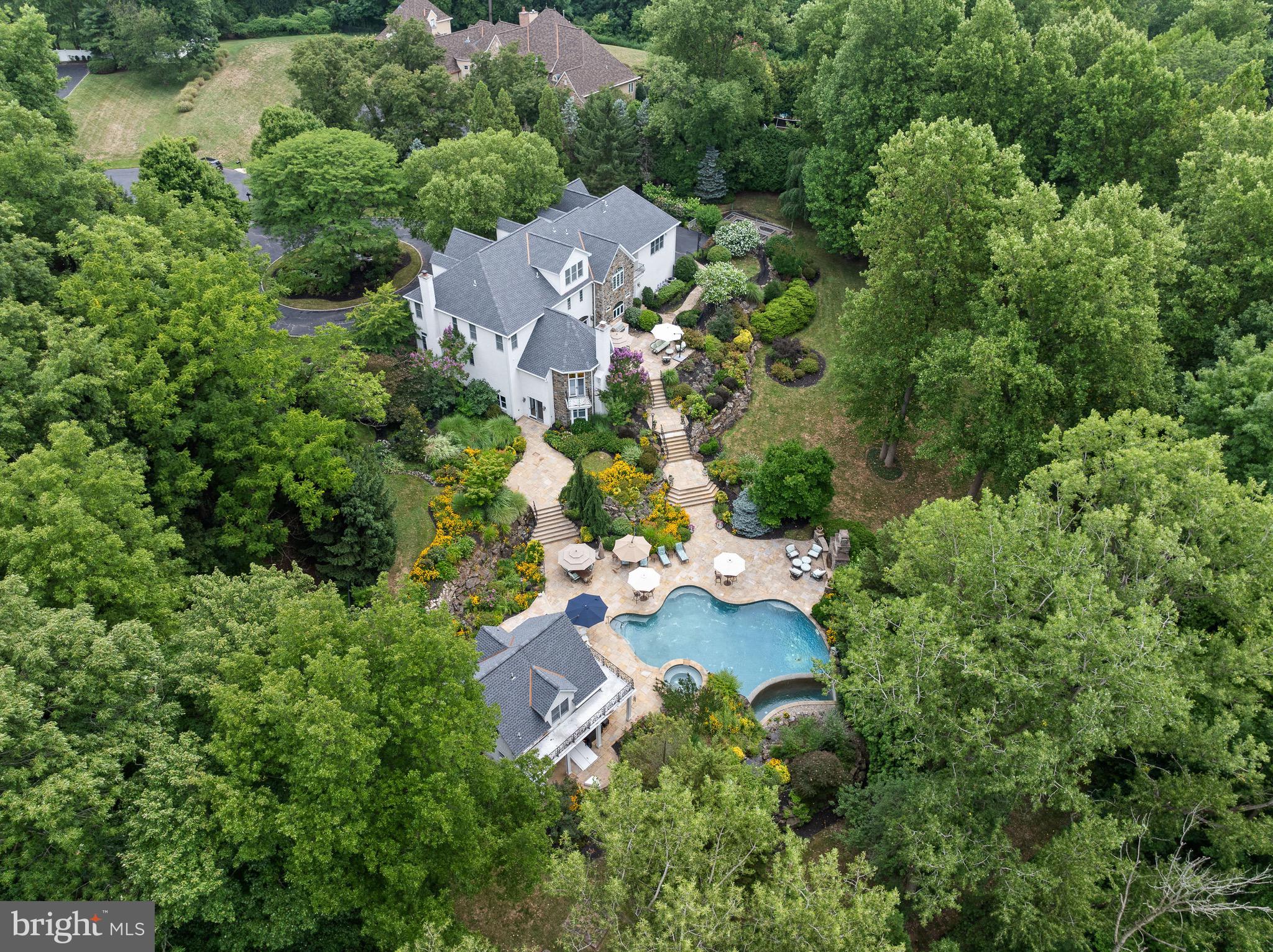 Be still my heart on Harts Ln... Escape to paradise at this luxury 10-acre estate on a private cul-de-sac in Whitemarsh Township. This one-of-a-kind property is a serene retreat where every day feels like a getaway, complete with luxurious amenities, stunning views, and a relaxing ambiance. It's a place where the rest of the world fades away, and you're enveloped in comfort and tranquility. The main house boasts over 8,000 square feet of living space, complete with 6 bedrooms, 6 full baths, a fully-finished walk out basement, a 4-car garage, and a spectacular backyard oasis. Also included on the compound is a 1,900 square foot guest house, perfect for multi-generational living, a caretaker/au-pair, or a private retreat for your house guests. The guest house features a living room, full kitchen, main floor full bathroom, and 2nd floor bedroom & ensuite bathroom. There is also a full basement for storage, outdoor bar & grill for entertaining, and a wrap-around balcony to take in all of the beautiful sights and sounds of the peaceful backyard. Immediately surrounding the home, you’ll find 3 fenced acres with an infinity pool, hot tub, Tennessee flagstone terraces, outdoor fireplace, flat grass backyard, horseshoe pit, vegetable garden, and extensive landscaping. Close your eyes and imagine this home being the place where all of your friends & family want to gather. Designed to evoke your sensory experiences, this backyard oasis is unmatched in attention to detail. Take in the sounds of the waterfall, chirping birds, mermaid fountain, and cracking fire in the outdoor fireplace. In the distance you can hear the clang of a horseshoe and a good friend’s laughter. Smell the delicious food simmering on the grill. Stroll the grounds to admire the colorful flowers and cozy ambience of exterior lighting. When you’re here, time slows down and you’re able to be fully present with your loved ones.
Beyond the estate fence is another 7 protected acres, mostly wooded to provide the ultimate privacy. Gracing the entrance of the main house is a koi pond with waterfall, a metaphorical exhale, creating instant zen. Step inside and you’ll be greeted by the grand foyer with 3-story turned staircase and custom wrought iron railings. This home exudes timeless elegance with its classic architectural details, refined finishes, and sophisticated design. The interior seamlessly blends traditional charm with modern luxury, featuring high ceilings, intricate moldings, and carefully curated materials. Every room offers an enduring style that transcends passing trends. At this property, the best of both worlds converge: Old world charm meets modern conveniences. Details such as extensive woodwork & trim, custom built-ins, walls of windows, charming fireplaces, gorgeous wrought iron railings & gates, add character and evoke another time, while modern conveniences like central surround sound, a biometric security system, temperature controlled wine cellar, and back-up generator ensure your ultimate comfort. The home has current upgrades/enhancements including: Brand new roof & gutters on both dwellings, replaced in 2023 with 25 year warranty/50 on materials; new kitchen appliances in 2020 including SubZero Professional freezer/refrigerator; new carpet on all stairs in main house, basement & owners suite in 2023; freshly painted owners suite 2023; new well pump in 2022; Lutron lighting system; World Wide Stereo surround sound throughout the property, Murano glass chandeliers & light fixtures in dining room; dog washing station; 4-Zone HVAC (new HVAC 2nd floor in 2020, new HVAC 1st floor in 2023; 2 hot water tanks in main house with 1 replaced in 2020 & the other in 2015; temp-controlled wine cellar; Kohler back-up generator, irrigation system supported by its own well; and the list goes on! 2040 Harts Lane will satisfy all of your heart’s desires, and it’s an experience that one must see to truly believe.