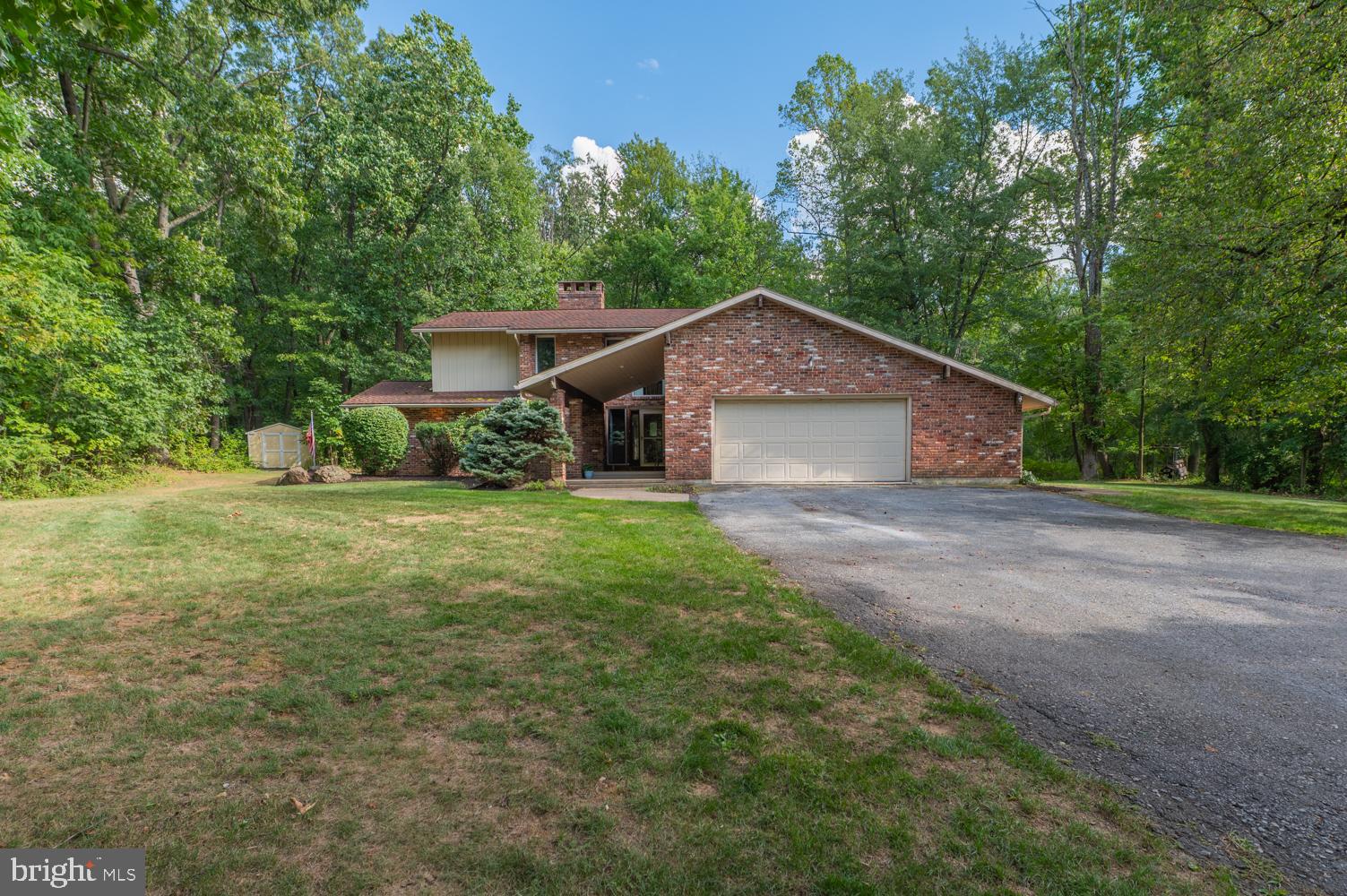Experience privacy and convenience in one stunning setting. Get ready to fall in love with this rare gem of a property, nestled on a 2.9-acre wooded lot within the Borough of Emmaus and East Penn School District. Follow the private drive to your own sanctuary featuring 3 bedrooms, 2.5 bathrooms, and more than 2,700 sf of living space. This custom-built single-owner home features mature landscaping, a covered front porch and covered rear patio, and is surrounded by trees for privacy. Delight in the brightness as you enter the hardwood foyer and see the natural light streaming through the multitude of windows in this contemporary home. The sunken family room has unique design features—from a statement brick fireplace to the French door access to the patio and a cathedral ceiling. The dining room with access to the large, covered patio flows seamlessly into the spacious eat-in kitchen. The first-floor primary suite and laundry room provide the convenience of one-floor living. Another full bath and two more sizable bedrooms—one with a walk-in closet or flex space—round out the second floor. A full basement is plumbed for a bath and is ready for finishing or to use as storage. The oversized garage and expanded parking pad provide plenty of off-street parking. Enjoy the walkable community with shops, restaurants, a farmer's market, schools, and parks all close by.