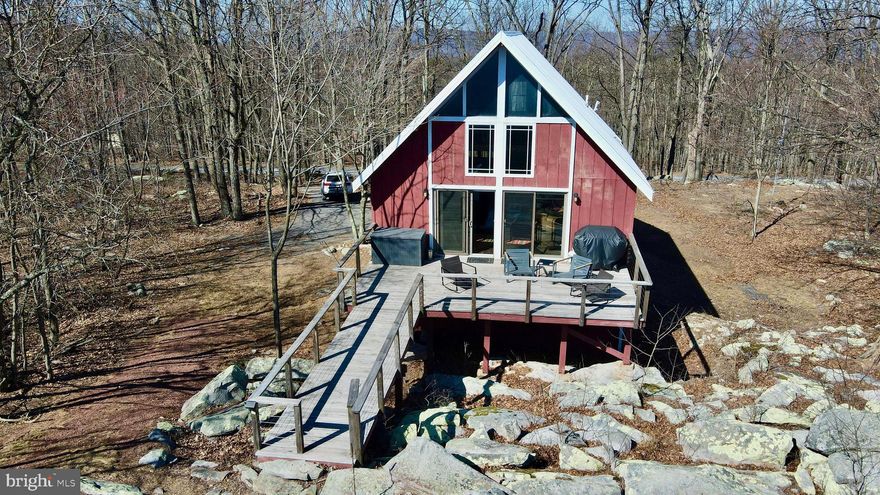 Secluded on almost 9 private acres in Great Cacapon, WV, this charming 3-bedroom, 1-bath cabin offers panoramic mountain views and a peaceful retreat into nature. With a perfect blend of rustic charm and modern comforts, this home is ideal for those seeking serenity, privacy, and outdoor adventure.  

Inside, the open and airy living space is enhanced by vaulted wood ceilings and expansive windows that flood the home with natural light while showcasing the breathtaking mountain scenery. The kitchen is thoughtfully designed with butcher block countertops, stainless steel appliances, open shelving, and a center island, creating a warm and inviting space for gathering and entertaining. The primary loft bedroom provides a cozy retreat with spectacular views, while two additional bedrooms offer comfortable accommodations for guests or a home office. The bathroom features natural wood accents, adding to the cabin’s rustic appeal.  

The finished lower level offers additional living space, perfect for a recreation room or office, with a pellet stove that provides warmth and a cozy atmosphere on cool mountain evenings.  

Stepping outside, the large deck invites you to take in the expansive, unobstructed mountain views. Whether enjoying a morning coffee, dining alfresco, or simply unwinding in the fresh mountain air, the outdoor space is designed for relaxation and connection to nature. The 10-acre lot is rich with wildlife, where deer roam freely and hummingbirds abound, bringing a magical energy to this secluded setting. Wooded trails provide endless opportunities for hiking, exploring, and immersing yourself in the natural beauty that surrounds the property.  

Whether you’re looking for a full-time residence or a weekend getaway, this mountain cabin provides the ideal balance of seclusion and convenience, with easy access to the Cacapon and Potomac Rivers, nature preserves, and outdoor recreation areas. Don’t miss your chance to own this peaceful mountain retreat.