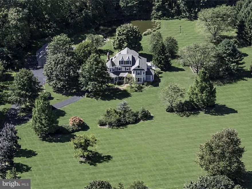 Impressive stately home has been completely updated and stylishly renovated with open interior floor plan and high-end modern appointments. Approached by a long drive, it's set on nearly 11 farmed acres, utilizing Tax Relief Act 319. Enjoy the tax benefits and atmosphere of the setting while it's farmed by someone else! Several porches, gazebo, stocked pond, slate patio, professional exterior lighting and landscaping make outdoor living irresistible. The interior features finished onsite hardwood floors throughout the main floor, upstairs hall and master bedroom. The living room's focal point is a stone fireplace with custom built-in surround, turret sitting area, open to the dining, breakfast and kitchen areas. Architectural columns create gentle but defined separations between the spaces. The kitchen features custom cabinetry, period subway tile backsplash, high-end commercial appliances, oversized island workstation/breakfast bar, built-in SubZero fridge, large walk-in pantry, with access to the side deck. The main-floor office, off the family room, is bright with skylight and French doors. Upstairs the master suite features a gas fireplace, walk-in closet, turret sitting area, and spa-like private bath. The master bath is incredible with catheral ceiling, frameless glass shower, oversized soaking tub, his/hers vanity and patterned marble floor. Three other bedrooms, hall bath, and upstairs laundry complete the second floor. The third floor makes a great office, craft or play area, with lots of additional storage and separate HVAC. A separate two-story outbuilding with half bath accommodates up to six full-size cars, and is currently used as a four-car garage with workshop. The backyard pond, natural gardens and farm-type setting is perfect for nature enthusiasts, with abundant wildlife and birds. Recently renovated, fresh and buttoned up, there is a new roof, newer HVAC, whole-house generator, and many other substantial features. Excellent location for commuters, and close to Newtown, New Hope, Doylestown and Peddler's Village. Rare find, and definitely a must-see!