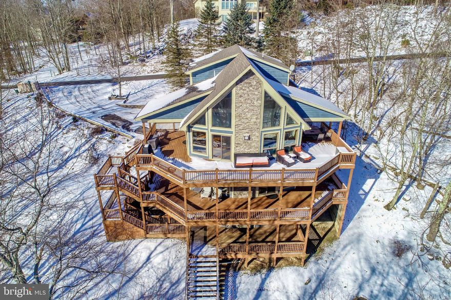 Mountain living meets the Deep Creek Lake lifestyle in this stunning five-bedroom, five-bath lake access retreat!  Offering dramatic architecture, generous living space, and a strong rental performance of $81,000 to $90,000.  The main level features soaring wood cathedral ceilings, a floor-to-ceiling stone fireplace to cozy up to after a day on the slopes, and a wall of glass in the open kitchen, dining, living areas.  The main level also includes two bedrooms and two full baths, one bath private to a bedroom, offering excellent flexibility for guests and main-level living.

The upper level is dedicated to a spacious primary suite with private deck, sitting area, walk-in closet, with a seperate area for owner lock up storage.  The spa like bath has a large jetted tub and a shower.  Just outside the bedroom is a loft overlooking the great room.

Lower Level one includes a spacious family room with a second stone fireplace and a wet bar, two bedrooms a full baths with a tub shower and a seperate shower.  A laundry room completes the picture.

Lower Level two offers a game room for family fun and an additional full bath.  Also a seperate room for storage, ski equipment, or owners lock up area. Step out to the hot tub to warm up and relax after skiing or being on the lake.

Enjoy wraparound decks on three levels with a covered dining and covered hot tub area. The lake access is minutes away with a clubhouse, picnic area, and swimming and kayaking on Deep Creek Lake. There is also a tennis court for the neighborhood! This home has an impressive annual rental income of $81,000–$90,000.  Located just five minutes from Deep Creek Lake State Park, and close to Wisp Ski Resort for four-season recreation! 

Call today to preview the many features this Mountain Lake Property has to offer!