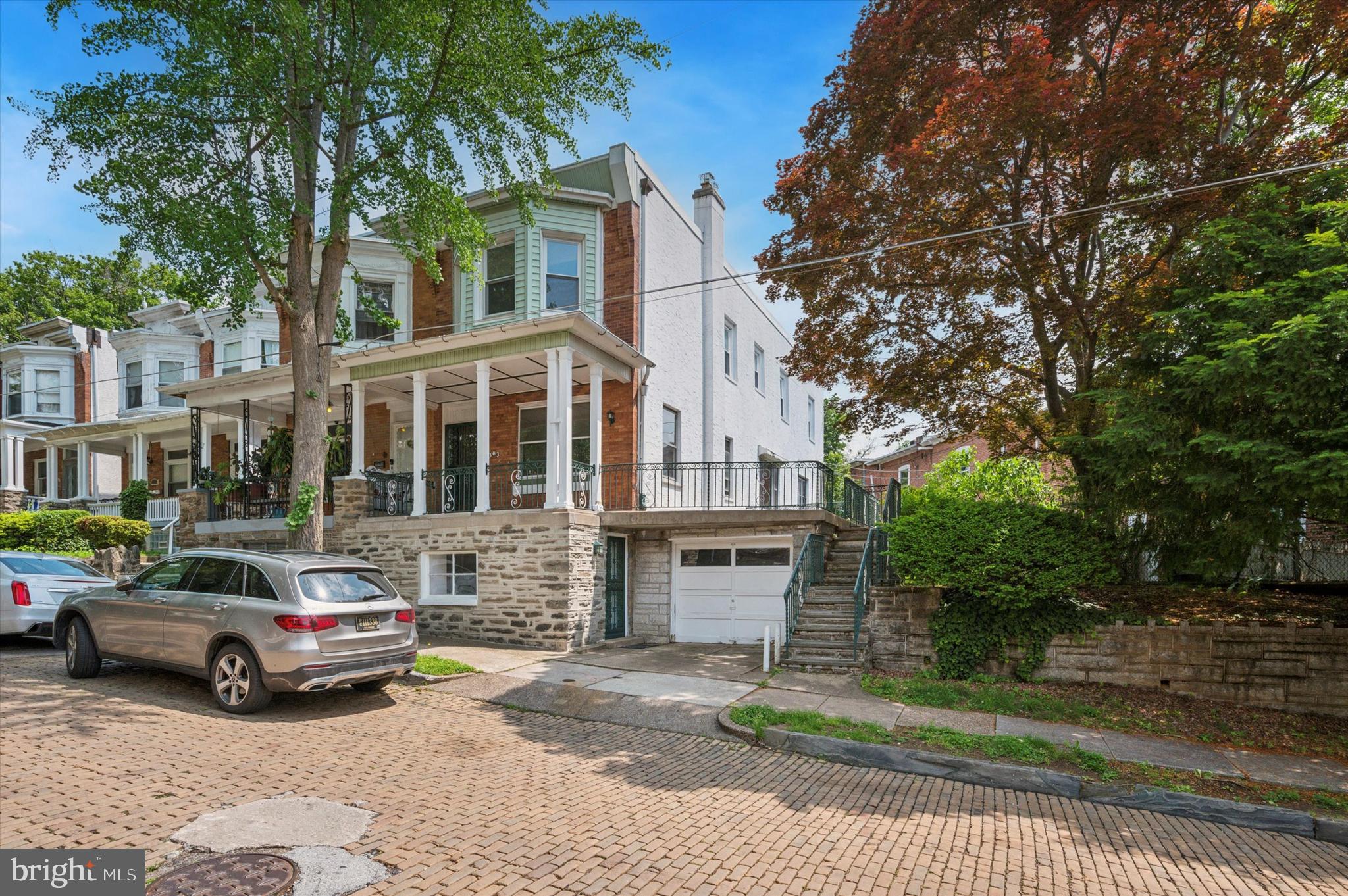 Welcome to this end-of-row home, with so much character, offering 4 spacious bedrooms and 1.5 bathrooms in a classic brick and stone exterior. Enjoy your morning coffee on the inviting covered front porch or entertain guests on the large side patio overlooking the fenced-in yard—perfect for pets, play, or gardening. Step inside to a grand living room featuring a faux fireplace with a wood mantle, marble hearth, and elegant wall sconces, all framed by tray ceilings and marble window sills. The generous formal dining room also features a tray ceiling and French doors leading to an updated kitchen complete with maple cabinets, brushed nickel hardware, ceramic tile backsplash, porcelain sink, soft-close drawers, double oven, and plenty of storage including a broom and pantry closet. Dual windows over the sink offer views of the patio and yard, and there’s also a direct exit to the rear outdoor area. Upstairs, the oak staircase with wood railings leads to a bright and airy primary bedroom, boasting three bay windows, two closets, and a tray/recessed ceiling. Three additional bedrooms and a ceramic-tiled hall bathroom with a tub/shower combo complete the second level. Enjoy high baseboards and gleaming hardwood flooring throughout the home. The partially finished basement offers a fantastic bonus space with a separate entrance, plus a large unfinished area ideal for storage or future expansion. The home also includes a 1-car garage, ornate railings, and timeless architectural details throughout. Don’t miss this unique and spacious home that blends character with comfort—schedule your showing today. all new windows just installed with a 10 Year warranty!