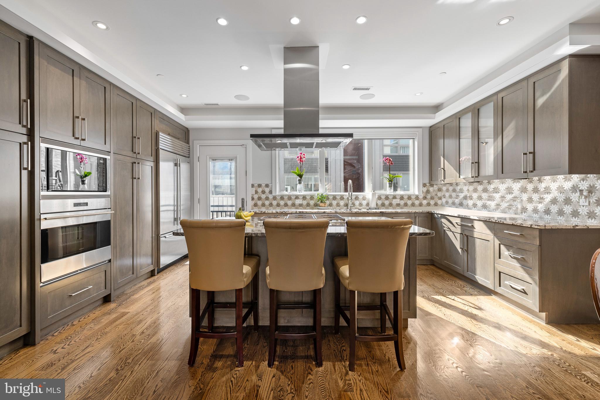 WHAT IF YOUR GETAWAY PLACE WAS HOME? ™ Nestled in the heart of Philadelphia’s Queen Village this 4500 sq foot luxury townhome checks all of the boxes. Offering ease of access to the city’s major teaching institutions, tech hubs, medical, pharma and financial centers; as well as the convenience of being minutes to air and rail transportation. While at home you can enjoy the walking to a playground, dog park, coffee shop, market and several restaurants that are all located within a two-block radius. Philadelphia’s Arts and Cultural facilities are also within walking distance.
Built in 2016 this was one of nine luxury townhomes constructed in the gated community of Shot Tower Estates; five years remain on the tax abatement. This home features three generous bedrooms, three full baths, two half baths, a wood paneled elevator that services all floors and a two-car garage that is electric car ready and offers with room for storage. The garage accesses the house through a main level foyer. On this floor you will also find an office or den with street views and an attached half bath. Just below on the lower level is a large finished basement ideal for those desire a recreation room, play room or large gym. The lower level is equipped with heated floors, an expansive wet bar and full bathroom that is also for handy overflow or sleep overs.
The Great Room is located on the second floor with stunning glass expanses, a gas fireplace that serves as a focal point with a tile surround and carved stone mantle. An open floor plan designed for entertaining reveals a Chef’s Kitchen with neutral custom hardwood cabinetry, handsome stone countertops, a mosaic tile backsplash and Wolf/Subzero appliance suite. Island seating and a built-in buffet and desk that doubles as a bar make this the perfect space for a gathering. Outside of the kitchen a balcony accommodates a grill and outdoor dining. The second powder room is adjacent to the dining area.
The second floor features two generously sized bedrooms with fantastic closeting and a well-appointed hall bath with tub shower and glass surround finished in wonderful neutral stone and tile. A full laundry room with sink and cabinetry and storage closet are also located on this level
An extraordinary main suite is afforded the privacy of a third floor. Outfitted with three walk in closets organized with built-ins, a gas fireplace, and sound surround this is truly a sanctuary. Completed by a spa like bathroom with a calming white finish, double custom vanities, an elegant soaking tub and oversized stone shower room with multiple shower heads. As expected in any spa the floors are heated.
On the uppermost floor a pilot house was designed to house a wet bar that services the massive rooftop deck with unsurpassed 360 degree views of both the city and bridge. Custom outdoor audio system creates the perfect spot for casual get togethers or to catch the fireworks.
Additional features include onsite stained oak hardwood floors and floating stairs, whole house audio, an alarm system with three keypads, video intercom and upgraded led gallery lighting throughout.