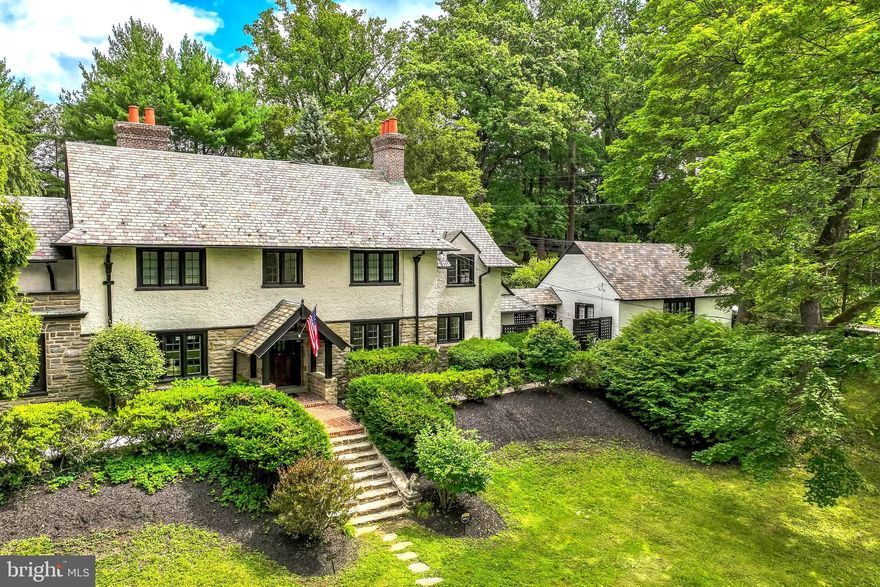 Nestled in the heart of Wayne, this stately Tudor-style Colonial sits on an exceptionally rare 1.4-acre lot and has been fully renovated in 2025, blending classic architecture with high-quality modern upgrades and character preserved. The home offers 4 bedrooms and 3.5 baths, plus an additional half bath in the detached garage and one in the basement. A welcoming foyer opens to a cozy living room and flows into a bright, airy family room filled with natural light from large windows. Custom built-ins, elegant French doors, and a charming fireplace create a warm atmosphere ideal for relaxing or entertaining. The sun-filled dining room connects to a wet bar/butler’s pantry leading into the kitchen. Upstairs, the primary suite includes a spacious bathroom with a soaking tub and access to a private roof deck. Three additional bedrooms and two full baths offer generous accommodations, while the attic provides flexible space for an office, studio, or extra bedroom. A massive basement with new windows and a new washer and dryer adds even more functional space and storage. The 2025 renovation also includes a fully rebuilt exterior entry staircase & landing and two new exterior pathways, a newly repaved driveway off Old Eagle School Road, and two added parking spots on Homestead Road. Outside, the property continues to impress with a detached three-car garage featuring three new automatic doors and a finished bonus area ideal for an office, gym, or storage complete with its own powder room. A fenced-in in-ground pool with a new safety cover sits beside the patio, and the expansive yard offers a large play area perfect for outdoor activities. This rare property combines acreage, privacy, and top-to-bottom renovation in one of Wayne’s most desirable locations.