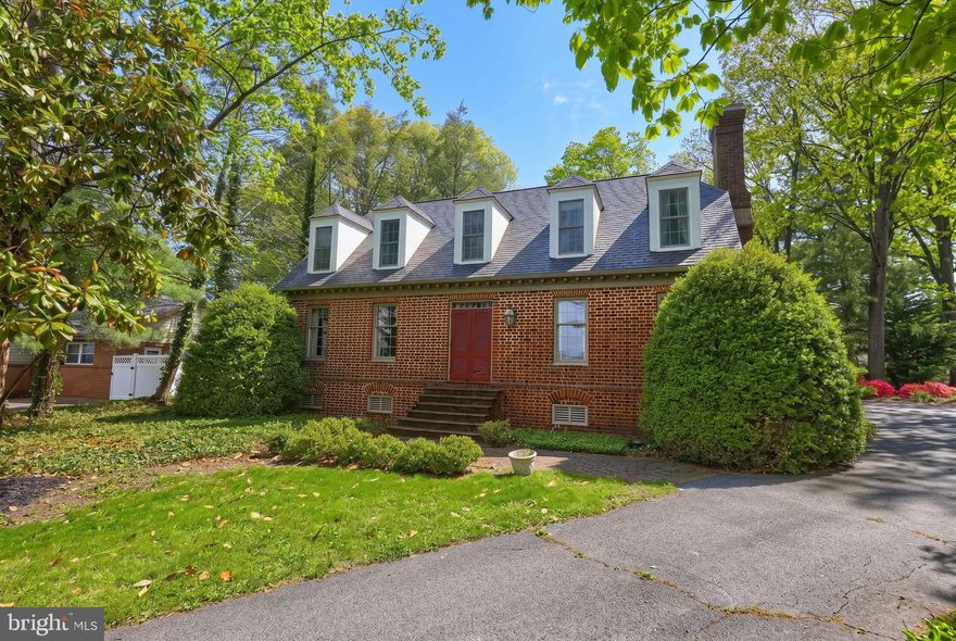 Timeless Colonial charm meets thoughtful modern updates in this 18th century style Colonial filled with character and warmth. Original architectural details shine throughout, including rich hardwood flooring, classic wood-burning fireplaces, and original woodworking that reflects the home’s historic craftsmanship.
A traditional center hall layout welcomes you into a spacious living room designed for entertaining, highlighted by a wood-burning fireplace. The formal dining room offers an elegant setting for gatherings and is conveniently located just off the kitchen, featuring a double oven and cooktop. Adjacent to the kitchen is a cozy den with an 18th century-style fireplace and built-in bar — the perfect space for relaxing or hosting guests. The upper level includes a spacious primary suite with generous closet space and an updated en-suite bath. Two additional bedrooms and an updated guest bath complete the second floor.
The finished lower level provides additional versatile living space with a recreation room, workshop area, and ample storage. Outside, the charm continues with a traditional smokehouse, expansive patio, mature shade trees, and beautifully maintained landscaping that create a peaceful backyard retreat. An oversized attached garage completes this exceptional property.