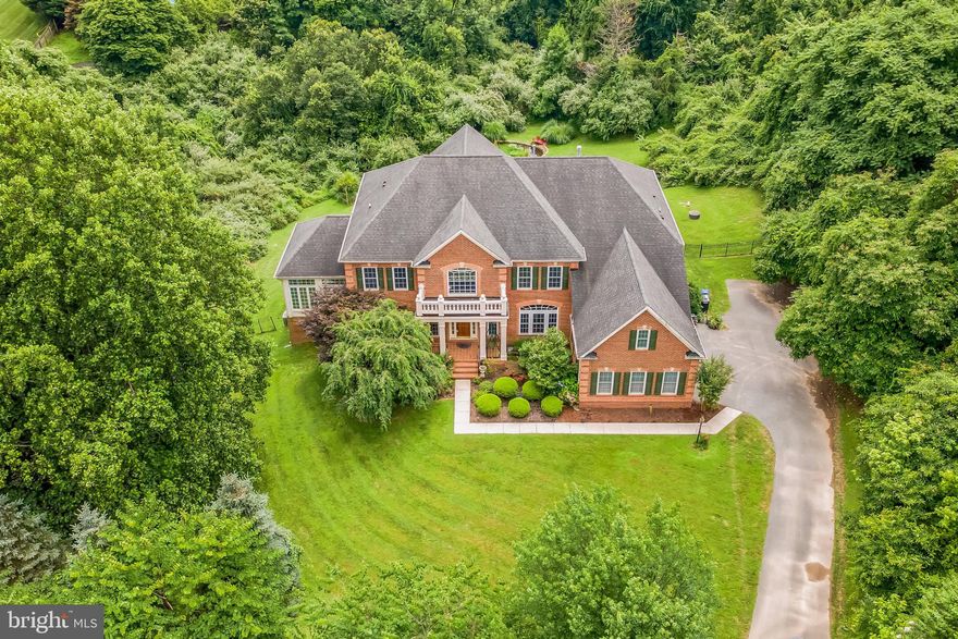 This stunning, freshly painted custom-built 9584 square feet  colonial home (No HOA Fee )  with striking brick walls encompassing the entire structure, situated on 1.6 acres of picturesque land. This property is beautifully enveloped by lush natural woods, offering a serene and private setting at the end of the community driveway. The home features a grand entry highlighted by elegant double stairways. Throughout the house, you'll find numerous architectural details, including a distinctive two-tone brick exterior, a coffered high ceiling in the expansive family room, and a dozen Roman columns that add to its grandeur. The design incorporates many exquisitely crafted floor-to-ceiling and arch-topped windows, ensuring the house is filled with natural light and possesses an elegant ambiance. There are Six  spacious bedrooms, each equipped with its own full bath and ample storage room. The residence also boasts a bright, pentagon-shaped breakfast room and a large conservatory with spectacular views and a luxurious marble floor. The enormous basement is fully finished and includes a theater, a game room, a poker room, and a wet bar, perfect for entertainment. The south-facing backyard ensures that the family room, kitchen, breakfast room, and master bedroom are bathed in sunlight throughout the day, contributing to the house's energy efficiency. Additionally, the first-floor office is connected to a full bath, offering the flexibility to be utilized as a bedroom.  3 HVAC System (Carrier Infinity. )  2015 by BGE Home, the top model , & There is no HOA fee.