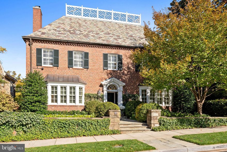 Situated on one of the most coveted streets in Kalorama and known as the Jelleff Mansion, a masterpiece of Georgian Revival architecture circa 1929, boasts timeless elegance and refined architectural detail. The stately brick façade is complemented by a steeply pitched slate roof adorned with decorative trim, enhancing the home’s sophisticated exterior. A pedimented entrance, featuring a graceful semi-circular fanlight, intricate pilasters, and finely crafted millwork, lends a distinguished and welcoming charm. The property exudes a commanding street presence, framed by beautifully landscaped gardens and meticulously maintained grounds. Step inside through the elegant entry vestibule, where marble floors transition seamlessly to the grand foyer. High ceilings create an immediate sense of space and light. The main level offers a perfect flow for entertaining, with impressive formal rooms and classic architectural elements, including paneled walls, thick crown moldings, and graceful archways. Multiple coat closets provide ample storage for guests.  The formal living room, of elegant scale, features an oversized bay window that floods the space with natural light. A central fireplace with a marble mantel from the Adams-period, circa 18th century, anchors the room, adding warmth and character. Adjacent is the handsome, wood-paneled library/study, offering built-in shelving, a second bay window, and an inviting atmosphere for work or relaxation. The formal dining room, spacious enough for grand-scale gatherings, can be enclosed and is enhanced with additional built-ins. Conveniently located next to the dining room, the updated kitchen offers abundant cabinetry, marble countertops, and high-end appliances, with table space for casual meals. A generously sized butler’s pantry provides extra storage and service space, making entertaining effortless. Additional conveniences on this level include a powder room, rear staff space, and a dedicated laundry room. Ascend the beautiful staircase to the second level, where a grand landing introduces the luxurious primary suite. Sun-drenched and spacious, the primary bedroom features a large dressing room with ample storage. The spa-inspired en-suite bathroom offers a frameless glass shower, a soaking tub, and refined marble finishes. There is a beautiful additional bath which is part of the primary suite. An interior hallway lined with closets leads to the generous private office/sitting room, which includes a fireplace. This level also hosts two additional well-proportioned bedroom suites, each with updated en-suite bathrooms, offering comfort and privacy for family members or guests. The top floor of the home, with soaring 10.5-foot ceilings, offers approximately 2,250 square feet of versatile space. Fully floored but awaiting customization, it currently serves as an oversized storage area with windows and multiple closets, presenting an incredible opportunity for future expansion or personalized living areas. The fully finished lower level provides abundant space for recreation and storage. A spacious family room with built-ins, a powder room, and a gym make this floor ideal for relaxation and fitness. A separate in-law or staff suite features a sitting room, bedroom, kitchenette, full bathroom, washer/dryer, and a private entrance, ensuring flexibility and privacy. This level also offers direct access to the one-car garage with storage. The rear exterior of the property is exceptionally private, perfectly tailored for both relaxation and entertaining. A flagstone terrace, mature trees, and lush professional landscaping create a serene outdoor retreat. There is also additional surface parking. This exquisite Georgian Revival home presents a rare opportunity to own a grand residence in one of Washington’s most desirable neighborhoods. Offering timeless elegance, generous living spaces, and meticulously maintained grounds, this property is truly one of Kalorama’s finest residences.