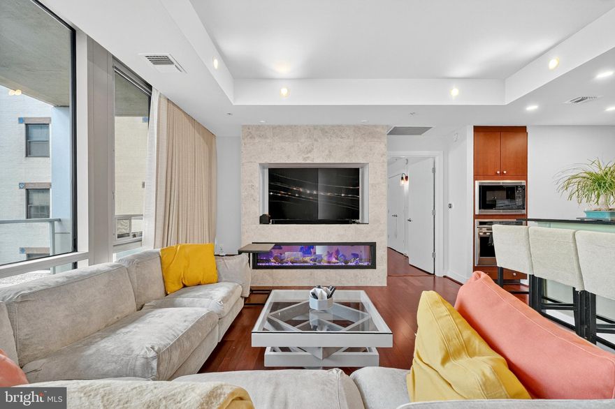 Welcome to The Adagio—luxury condominium living in the heart of Chevy Chase / Bethesda. Residence #4006 offers 3 bedrooms, 3 full baths, and a large private balcony with tranquil courtyard and tree-top views. Floor-to-ceiling windows flood the home with natural light, complemented by open-concept living and dining spaces anchored by a custom electric fireplace and built-in media wall, as well as a thoughtfully designed custom bar installation that enhances both functionality and entertaining. The chef’s kitchen is appointed with premium appliances including Sub-Zero refrigeration, Wolf double ovens, Bosch and Miele, further elevated by a custom backsplash, upgraded lighting, and dimmers throughout. The home has been extensively improved with designer finishes, including full interior paint across all walls, doors, and moulding, along with carefully selected lighting fixtures that create a cohesive and elevated aesthetic. All three bedrooms are thoughtfully designed with professionally installed custom closets, built-in desks, shelving, and wall sconces for layered lighting—offering exceptional flexibility for guest use, work-from-home needs, or both. The primary suite features a spacious custom walk-in closet and a spa-like bath with double vanity and soaking tub. Additional highlights include remote-controlled Hunter Douglas custom blinds and curtains throughout, custom window treatments, a separate laundry room with high-end washer/dryer and added custom shelving, and multiple appliance upgrades including a new dishwasher. The home is also equipped with two newer Carrier HVAC systems paired with Nest thermostats for modern efficiency and comfort. Additional design enhancements such as wallpaper accents and upgraded fixtures further contribute to the home’s turnkey condition. Two garage parking spaces and a private storage unit convey. The Adagio is a full-service, 24-hour concierge building featuring a fitness center, library, social lounge, guest suite, landscaped courtyard, guest parking, and recently renovated common areas. Unbeatable location moments from shopping, dining, parks, and Metro access. A rare opportunity to own a fully upgraded, turnkey luxury residence in one of Bethesda’s premier buildings. HOA dues cover gas and water. Furniture can be included in the sale