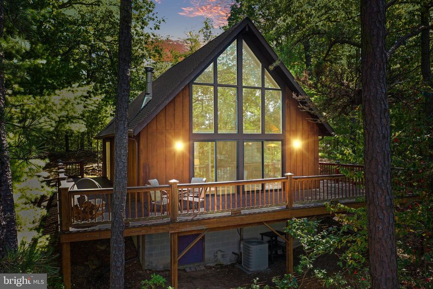 Panoramic, mountaintop views surround this private 3 bedroom, 2 bath cabin perfectly sited among towering pine trees high on a mountain ridge. This modified A-frame style cabin features tons of natural light pouring in through a wall of glass looking out to a never-ending sky of mountaintops.  The dramatic 2 story vaulted ceilings clad in tongue & groove pine, evoke a tremendous sense of coziness. The open concept living area is thoughtfully laid out with a wood-burning stove that can be enjoyed from the  living room/ dining room/ kitchen. From the lofted second story overlook you can see forever, the steel cable railing leading upstairs is just the right kind of update that evokes a little touch of modern aesthetic. The entire front wall of the home is framed in glass, giving way for the stunning ridge-top views and sunsets to be enjoyed from all of the living and entertaining spaces.  This cabin was thoughtfully designed with a primary bedroom on the first floor with sliding glass doors to the deck and an en-suite bathroom with jetted soaking tub,  washer and dryer hookup. A fire pit in the front yard completes the package, it is truly idyllic! The home features central heat and air conditioning and is offered mostly furnished making it completely turnkey. Located just two hours from the DC Metro area in the heart of the sought-after Lost River, this property is served by high-speed fiber optic internet and all underground utilities. Nearby entertainment & shopping - less than a mile to the Guesthouse Lost River and within a few miles of nearby local markets, shops & businesses. The Lost River State Park and George Washington National Forest, just a few miles away, feature thousands of acres of hiking trails, horseback riding, and more. CLICK on the camera icon for a 3D Virtual Tour