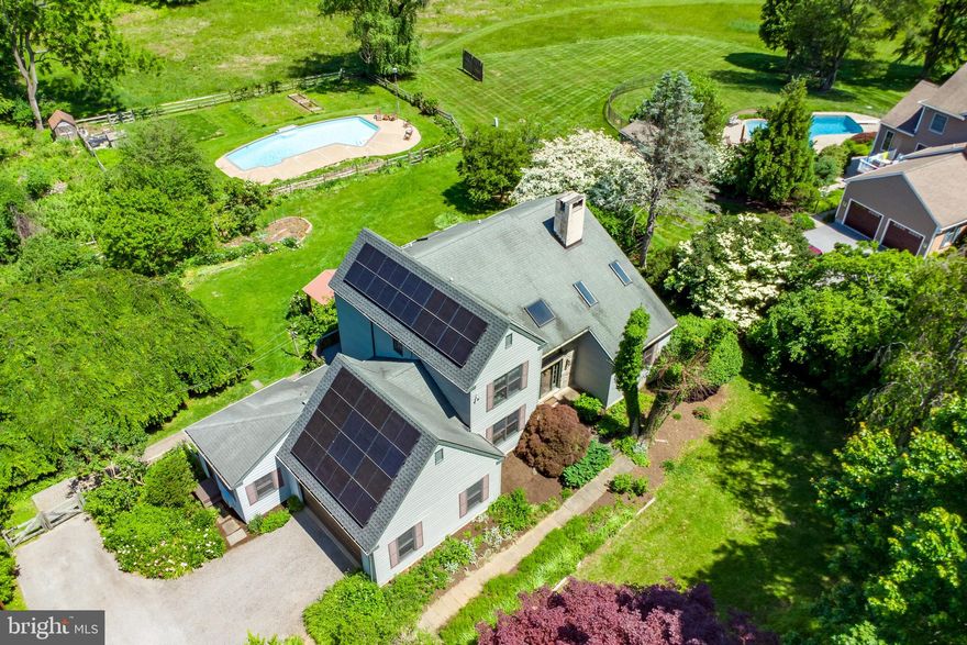 Welcome to 1019 Ashley Road, a beautifully designed 3-bedroom, 3.5-bathroom home tucked away near the end of a quiet, tree-lined cul-de-sac in the desirable Plumly Farms neighborhood of Westtown Township. Set back from the street surrounded by mature landscaping, this thoughtfully maintained property blends charm, space, and sustainable living—all within walking distance to Bayard Rustin High School and a short drive to shopping, dining, and downtown West Chester. Step inside to an inviting entryway featuring hardwood floors, vaulted ceilings, and skylights that fill the space with natural light. The formal dining room boasts elegant crown molding, chair rail, hardwood floors, and a statement ceiling light—perfect for entertaining. Across the hall, the living room offers vaulted ceilings with exposed beams, hardwood flooring, skylights, and a decorative fireplace for added warmth and character. The cozy family room features an exposed wood-beam, another striking stone fireplace with a Quadrafire Expedition 2 insert for winter heating (peak BTU/hr 56,000), and French doors that open onto an expansive two-level deck. The adjacent breakfast room includes sliding doors to the upper deck, chair rail accents, and a decorative fireplace. The chef’s kitchen is equipped with soapstone countertops, stainless steel appliances, peninsula seating, a prep sink, pantry, and energy-efficient appliances. A private home office with a vaulted ceiling, triple window with serene yard views, built-in desk and shelves—plus a separate entrance—makes working from home a breeze. The main level also includes a mudroom with access to the garage and deck, a laundry room with utility sink and workspace, and a powder room off the foyer. Upstairs, the spacious primary suite offers a unique loft overlooking the living room, a walk-in closet, and an en-suite bath featuring a jetted tub, walk-in shower, skylight, and tile flooring. Two additional bedrooms—one with hardwood floors, the other with carpet and a custom closet—share a Jack-and-Jill bathroom with a double-sink vanity and tub/shower. The finished lower level functions as a full in-law suite with its own private entrance, second kitchen, living area, office nook, bedroom space, and full bath—ideal for guests or multi-generational living. Step outside to a true backyard oasis: a large in-ground pool with waterfall, a charming detached pavilion, a brick pizza oven, and lush, established landscaping. The wooded area has been cleared of invasives, ready for new native plantings. Seasonal color abounds with sugar maples, magnolias, dogwoods, lilacs, cherries, redbud, rhododendrons, and more. Edible landscaping includes beach plums, goumi, pears, nectarines, pawpaw, peaches, elderberries, raspberries, blackberries, currants, gooseberries, hazelnuts, and a cleared space perfect for a garden. This energy-efficient home includes a 7.3 kW solar system (fully paid), high-efficiency heat pump, EV charger, energy-efficient windows, programmable thermostat, Energy Star appliances, and mature shade trees to keep you cool and reduce energy use. Beyond the beautifully landscaped backyard lies a breathtaking open-space vista with access to walking trails along Chester Creek and through flower-filled fields. Enjoy the sounds of owls and spring peepers by night—all just minutes from the borough, parks, and top-rated schools. 1019 Ashley Road offers unmatched comfort, character, sustainability, and location. Schedule your private tour today and experience it for yourself!