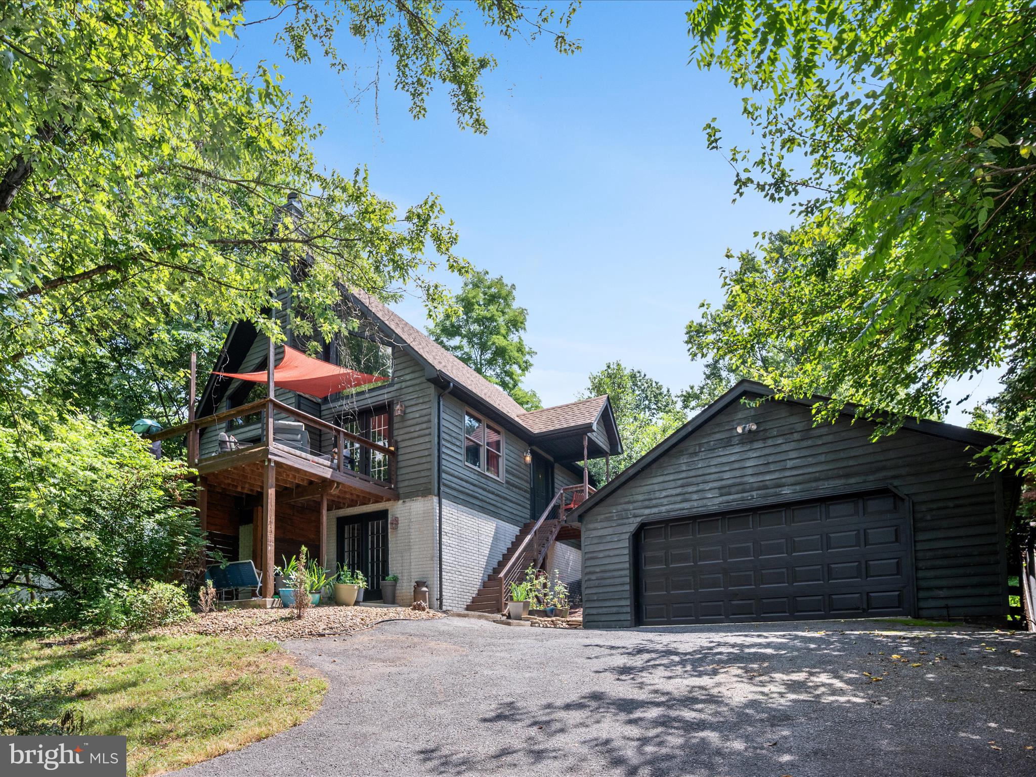 This grey-stained cedar-sided chalet tucked in the trees is an artist’s dream and a nature lover’s retreat! This meticulously maintained home welcomes you with warmth and character at every turn. Nestled in a private setting near the Potomac River—complete with deeded river access—you’ll enjoy peaceful surroundings just 10 minutes from vibrant Shepherdstown, WV.
Inside, the layout is both modern and functional. The main level features an open kitchen with stainless steel appliances that flows into a vaulted dining and living area centered around a cozy wood-burning fireplace. A main-level bedroom and full bathroom offer easy accessibility, and the convenient laundry room walks out directly to the backyard. Upstairs, a lofted flex area leads to a second bedroom and full bathroom—ideal for guests, a home office, or creative space.
The partially finished basement is a standout feature, offering a walk-out to the lower patio and a full entertainment room complete with a projector and screen—your own private movie night haven! There's also an unfinished room perfect for storage or future customization.
Outside, the spacious deck and lower patio invite you to relax, entertain, and connect with the surrounding natural beauty. A large detached garage adds even more space for hobbies or gear. Whether you're looking for a full-time home or a weekend escape, this one-of-a-kind chalet offers the perfect mix of tranquility, modern design, and access to both river adventures and the lively energy of a nearby college town. Schedule your showing today!
