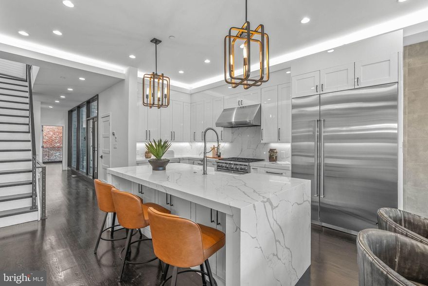Experience a rare blend of architectural precision and modern convenience in this exceptional Northern Liberties townhome, thoughtfully designed for elevated city living. This residence spans multiple levels connected by a private five-stop elevator and features four spacious bedrooms, each offering its own en-suite bath and walk-in closet. The chef’s kitchen anchors the home with a dramatic waterfall quartz island, solid stone backsplash, Sub-Zero refrigeration, a Wolf six-burner range, and a fully outfitted pantry complete with coffee station, secondary sink, and beverage refrigerator. Designed with both lifestyle and flexibility in mind, the home includes a custom-built gym with kitchenette that can easily function as a private office or studio. The heated four-car garage is equipped with an EV charger and dedicated workstation, while integrated Russound audio with twelve zones delivers seamless sound throughout the home. The first-floor suite is wired for a 5.1 theater setup and features a tranquil meditation space accented by backlit onyx stone and a gold-leaf ceiling. Expansive floor-to-ceiling windows with motorized Hunter Douglas shades flood the interiors with natural light, highlighting the white oak flooring throughout. Outdoor living is elevated on the rooftop deck, finished with Trex decking, speaker system, and cable readiness, offering sweeping skyline views ideal for entertaining or relaxing. Additional features include a comprehensive Xfinity security system with hardwired interior and exterior cameras and a Nest/Google Home–integrated network video recorder, completing a home that balances luxury, technology, and thoughtful design at every turn. Tax abatement ends 3/2029. Garage parking for up to 4 vehicles (Tandem Configuration). Taxes and square footage is the responsibility of the buyer to have verified independently. Some photos have been virtually staged.
