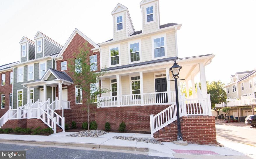 This newly constructed end-unit townhome at 300 Dixon Street offers a bright, spacious, and efficient four-level layout just a few blocks from downtown Easton. Finished in cream-colored Hardie Plank siding, the residence benefits from extra side windows that bathe the interior in natural light and a distinctive wrap-around porch—extending along both the front and side.

Level 1 – Garage & Service:
The ground level features a private garage with rear entry and direct access. This level also includes a half bath, a versatile bonus room, a dedicated laundry room, and a utility closet—ensuring everyday convenience and ample storage.

Level 2 – Main Living Area:
Step through a welcoming foyer into an open-concept space that seamlessly integrates the living room, a well-appointed kitchen, and an eat-in dining area. The kitchen is equipped with GE stainless steel appliances (cooktop, double wall oven, hood vent, dishwasher, refrigerator, and garbage disposal), complemented by upgraded quartz countertops and custom Timberlake cabinetry. Sliding glass doors lead to a balcony that fills the space with natural light, while a half bath, a coat closet, and a pantry round out the level. High ceilings, recessed lighting, and crown molding further enhance the inviting ambiance.

Level 3 – Bedrooms & Full Bathrooms:
Designed for comfort and privacy, the third level houses three bedrooms and two full bathrooms. Both full baths have been upgraded with quality Moen fixtures, glass shower doors, tile floors, quartz countertops, and custom Timberlake cabinetry, with white subway tiled showers. The primary bedroom suite features a generous walk-in closet and an expansive primary bathroom complete with a dual vanity and two storage closets for toiletries and linens. Carpeted bedrooms and hallways add a cozy touch throughout.

Level 4 – Loft:
The flexible loft, complete with its own mini split unit for heating and air conditioning, offers an adaptable space ideal for a home office, playroom, or additional living area. Abundant natural light makes this top level particularly inviting.

Community & Location:
Unit 201 is part of the Dixon Square Townhouses in Easton, located in Talbot County at the heart of Maryland’s Eastern Shore. The property is bordered by the nearly three-mile Easton Rails-to-Trails, offering recreational opportunities and convenient access to local shops, parks, and other destinations. Dixon Square itself features charming streetlights, brick stairways, sidewalks, and beautifully maintained landscaping managed by the HOA—making homeownership both enjoyable and low maintenance. Whether you’re drawn to outdoor adventures, the arts, festivals, or dining at a diverse mix of locally owned restaurants, this vibrant community provides endless opportunities to live your best life.