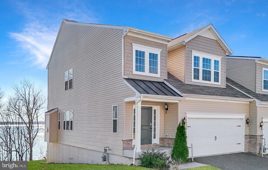 Ever heard of the Blue Mind theory? It’s the scientific connection between water and happiness.   It is the way being near water lowers stress and boosts creativity. Now, you can experience it every day in this beautiful, newer end-unit villa.
Tucked away at the end of a quiet street within a 55+ community, this home is more than a residence; it’s a peaceful waterfront sanctuary.  It features a two-story foyer that leads into an airy, open floor plan wrapped in windows.   The spacious kitchen serves as the heart of the home, featuring a massive central island.  Relax by the fireplace while watching the seasons change over the water.
This home offers a rare layout where four out of the five bedrooms feature direct seasonal water views.  The convenient primary suite is a private haven located on the first floor, offering serene morning vistas.  A versatile upper level space is great for guests or hobbies, featuring three bedrooms, a loft, a bonus room, and a full bath.  A spacious walk-out lower level includes a wet bar, an additional bedroom, and a full bath.   This area is perfect for an in-law suite or even the ultimate entertaining room.  Enjoy the fresh air from two rear decks overlooking the water. Whether you’re hosting a summer BBQ or enjoying a quiet morning coffee, the backdrop is unmatched. Complete with a two-car garage and a secluded location, this spacious villa truly offers it all.