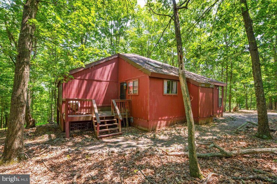 Nestled on a wooded 1.09-acre lot, this inviting 3 bedroom, 2 bath cabin offers the perfect blend of rustic charm and modern comfort—ideal for year-round living or weekend getaways. Located in the heart of The Woods Resort, this home provides easy access to a wide array of amenities while still offering privacy and tranquility. Step inside to a spacious open-concept main living area with vaulted ceilings, wraparound windows, skylights, and a cozy wood-burning fireplace—creating a bright and welcoming atmosphere. The living room flows seamlessly to a wraparound deck, perfect for enjoying peaceful mornings or entertaining under the trees. A separate dining area with skylight opens to a screened-in porch, offering the best of indoor-outdoor living. The large kitchen has plenty of counter space for gatherings and includes a washer and dryer thoughtfully tucked under the counter for added convenience. Two generously sized bedrooms with vaulted ceilings and two full baths are located on the main level. Upstairs, a charming loft bedroom adds a unique and flexible space for guests. While the cabin could benefit from some exterior repairs and interior updates, it has been priced accordingly and presents an excellent opportunity to create your dream retreat. Enjoy all that The Woods Resort has to offer including an award-winning 18-hole golf course, indoor and outdoor pools, fitness center, spa, tennis, pickleball, racquetball and basketball courts, a restaurant and pub, hiking trails, stocked fishing ponds, and more. This amenity-rich community spans over 1,800 scenic acres and is short-term rental friendly, making this property a great option for investment or personal use. Don’t miss your chance to own a piece of this peaceful and active mountain lifestyle!