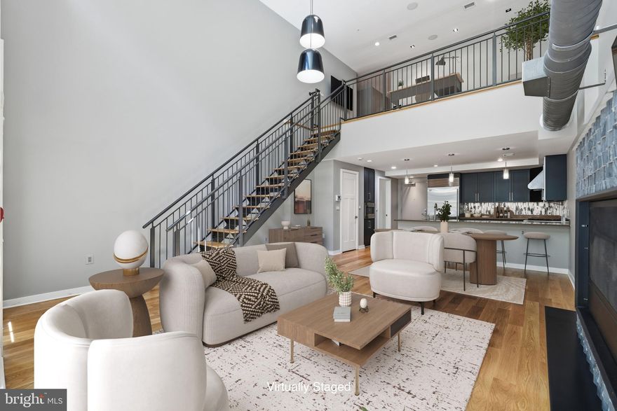 1610 N. Queen St #241 in Gaslight Square presents a residence where industrial edge is thoughtfully refined, creating a home that feels both architectural and deeply livable. Positioned in the heart of Rosslyn, one of Northern Virginia’s most connected and dynamic urban hubs, this address offers immediate access to the energy of the city while maintaining a sense of a natural retreat within Gaslight Square’s landscaped interior courtyards.

The great room delivers immediate impact. A dramatic 20-foot window wall floods the space with natural light, casting light across 5 inch plank solid wood floors and emphasizing the vertical volume. Motorized shades allow you to shift the atmosphere from bright and open to more intimate in seconds. The aesthetic leans industrial, but the execution is polished.

A glass door opens to a private, brick-walled terrace that feels distinctly urban yet unexpectedly quiet. From here,  you can access the interior courtyard and both Quinn and Queen Streets. This is a lovely entry point for guests, family, and friends.

Living, dining, and gathering spaces unfold seamlessly, creating a cohesive environment that feels both expansive and grounded. The floating gas fireplace, wrapped in New Wave Silver Mosaic tile, introduces texture and serves as a subtle focal point. Driftwood-style log and a custom mantel enhances the composition, while a trio of Marcel Wanders Black Can-Can pendants adds a sculptural presence overhead.

The kitchen is fully integrated, designed as both a workspace and a design feature. Custom European cabinetry, quartz surfaces, and a hand-laid mosaic backsplash create a layered, tactile backdrop. A Wolf gas range, Sub-Zero refrigerator, and Asko dishwasher anchor the space, while the oversized island with bar seating becomes a natural place to gather. Pantry cabinetry with a built-in microwave keeps everything streamlined.

A dedicated dining area fits comfortably within the footprint, allowing the space to flex effortlessly between everyday living and entertaining.

Off the doorway to and from the garage is a well-appointed powder room for life’s necessities, along with a coat closet for practical storage.  The deeded garage space #207 comes equipped with 3 large storage cabinets and is directly in front of the condo, making grocery hauling and everyday comings and goings safe from the elements. 

As you head upstairs, the floating staircase continues the home’s architectural language. A thoughtfully positioned loft adds flexibility, offering an ideal setting for an office, reading lounge, or quiet retreat that feels connected yet distinct from the main living spaces. This level also benefits from a secondary entrance off the secure building lobby, providing convenient access to mail and package delivery and a more private area to greet unknown visitors or contractors. 
 
On this level,  you will find the bedrooms, mechanical systems, and laundry. The primary suite is calm and refined, with French doors opening to a second private patio. The bath features clean lines, a dual head walk-in shower, a two sink vanity, and understated finishes. A secondary bedroom and hall bath with Porcelanosa tile completes this level.

Gaslight Square offers a unique blend of classic design and courtyard-style living, creating a quieter, more intimate setting within Rosslyn.

And just outside, Rosslyn delivers exactly what you want it to. Metro, dining, coffee, and everyday essentials are all within easy reach, along with quick access to DC via Key Bridge. It is a location that balances energy, accessibility, and ease.