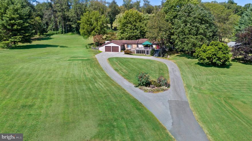 Welcome to this unique and stunning raised ranch home set on 13.03 acres in the serene area of Yorklyn which borders Hockessin & Greenville. Formerly Snuff Mill Tree Farm, this property is one of the few remaining farms in New Castle County offering a coveted farm tax exemption, providing remarkably low taxes. Ideal for those interested in farming, raising animals, or equestrian pursuits, this expansive land also offers potential for building additional structures or subdivision with due diligence by the buyer. The impeccably maintained home offers one-level living at its finest. A long, winding circular driveway crossing over a creek leads to a charming front deck with an awning, perfect for enjoying the breathtaking views of the surrounding nature and deer grazing in the pastures. Enter through the double doors to a vaulted foyer featuring a cozy gas fireplace, which opens to the spacious dining and living rooms. The main hallway leads to a guest bedroom and a primary suite, offering a spacious retreat with cathedral ceilings, ample closet space including a walk-in, and a newly renovated ensuite bathroom. On the opposite side of the home, you’ll find the gourmet kitchen, boasting solid wood custom cabinetry, granite countertops, and some newer appliances. The adjoining breakfast area with a two-sided stone fireplace provides a stunning view of the grounds through triple French doors. An adjacent step-down family room with exposed beams and a fabulous screened-in porch offer additional living space. The porch overlooks an inground kidney-shaped swimming pool with a waterfall and paver patio—perfect for summer relaxation. Back inside, the main level is completed by a half bath, separate laundry room, two additional bedrooms, and a full bath. Curved stairs lead to the finished lower level, which features a spacious recreation room with a gas fireplace, a craft room, office space, and a potential fifth bedroom or flex space. This level also includes a full bathroom, ample unfinished storage space, and a workshop area. From here, walk out to an enclosed brick patio. Outside, the property offers a wood shed and a poly house for growing plants and vegetables. Additional features include 2x6 framing during construction, 3/4-inch hardwood flooring, extra insulation, newer HVAC, a new water heater, a new septic tank, and a distribution box. This rare opportunity combines rural charm, modern amenities, and endless possibilities.